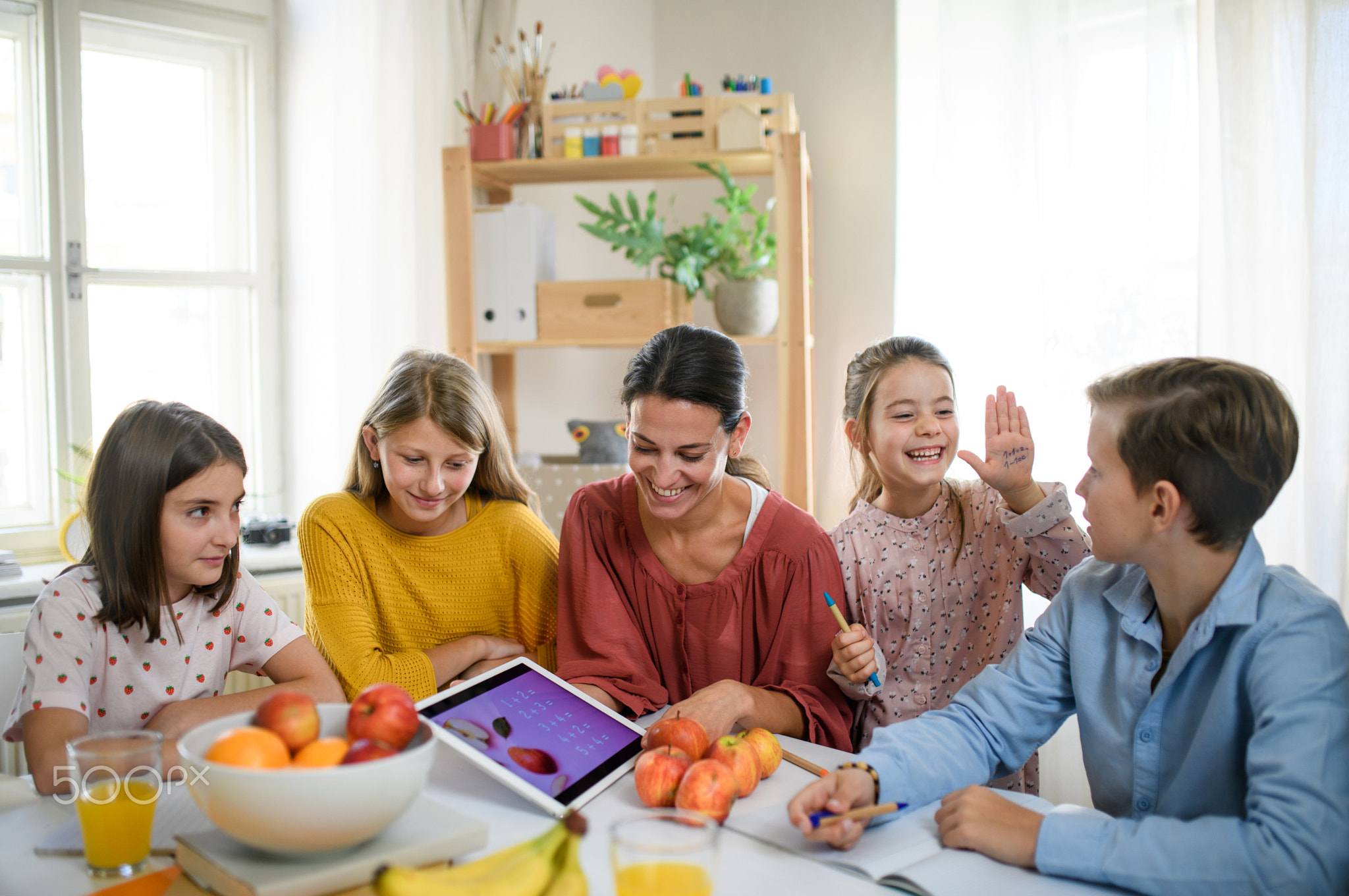 Group of homeschooling children with teacher studying indoors