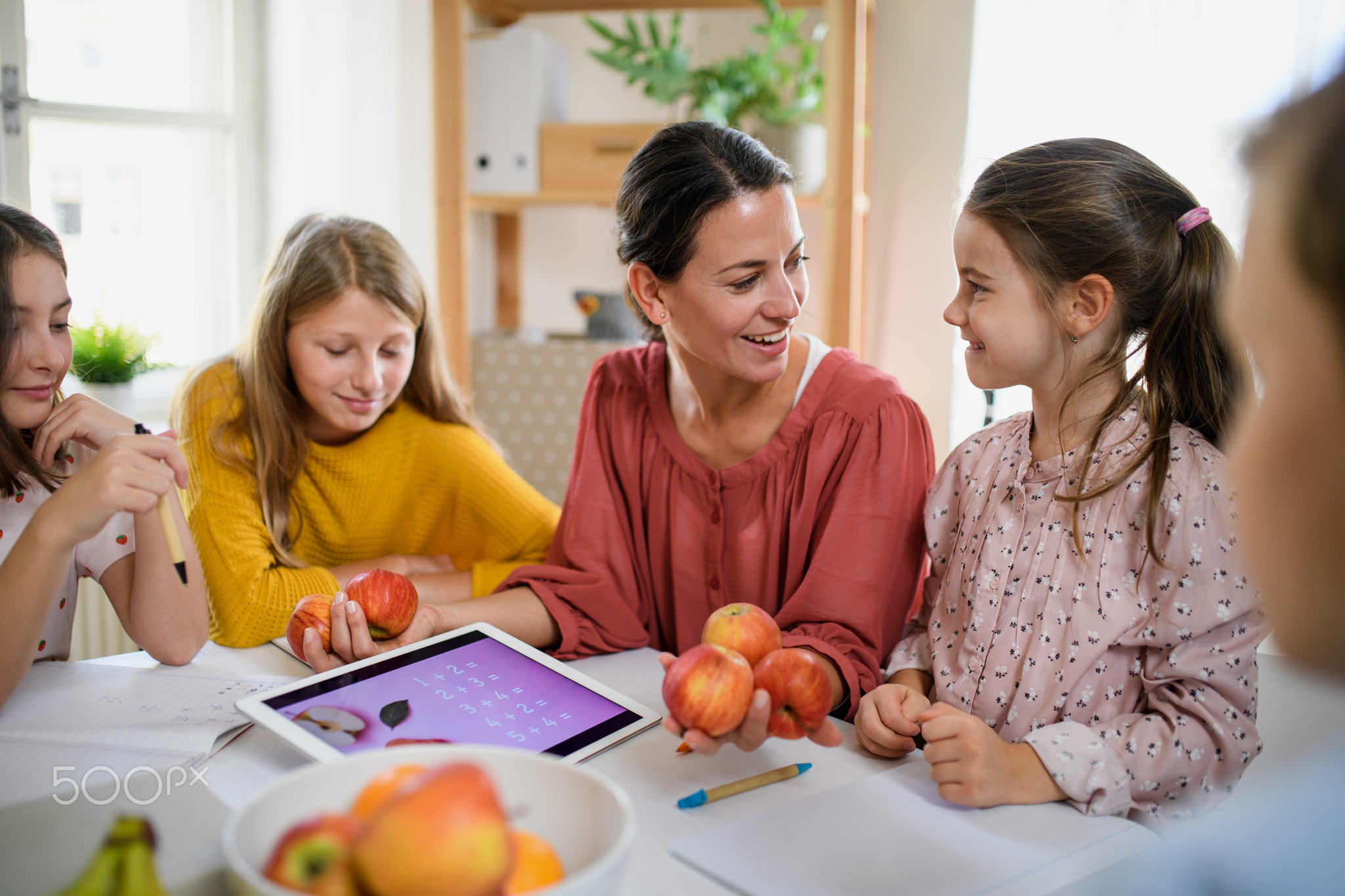 Group of homeschooling children with teacher studying indoors