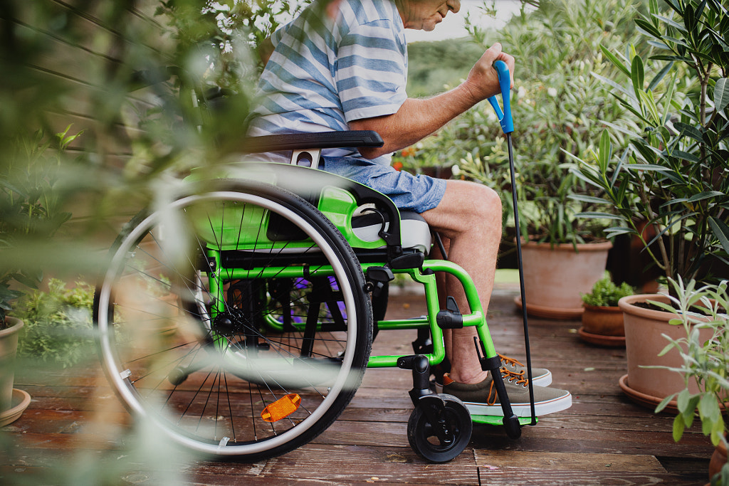 Unrecognizable senior man in wheelchair doing exercise on terrace. by Jozef Polc on 500px.com