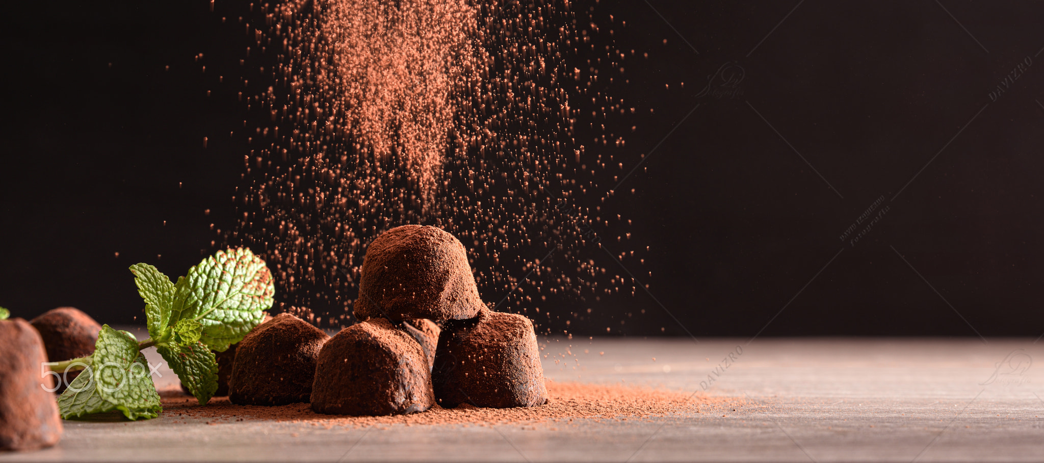 Chocolate truffles with mint leaves on wooden table dark background