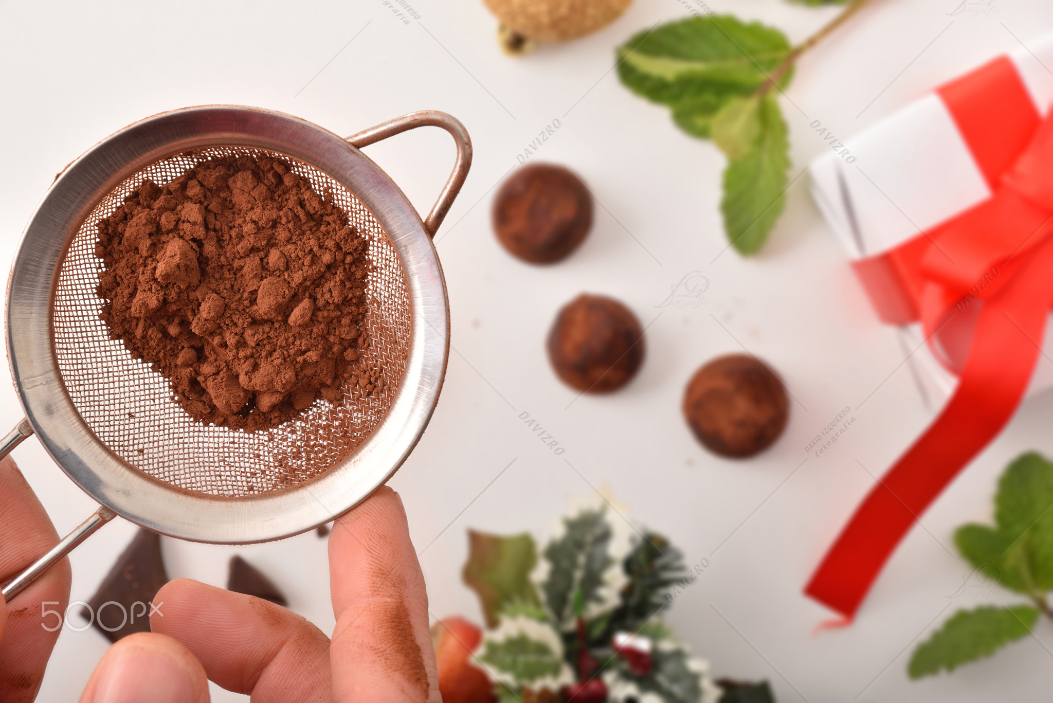 Hands pouring cocoa powder into chocolate truffles top view