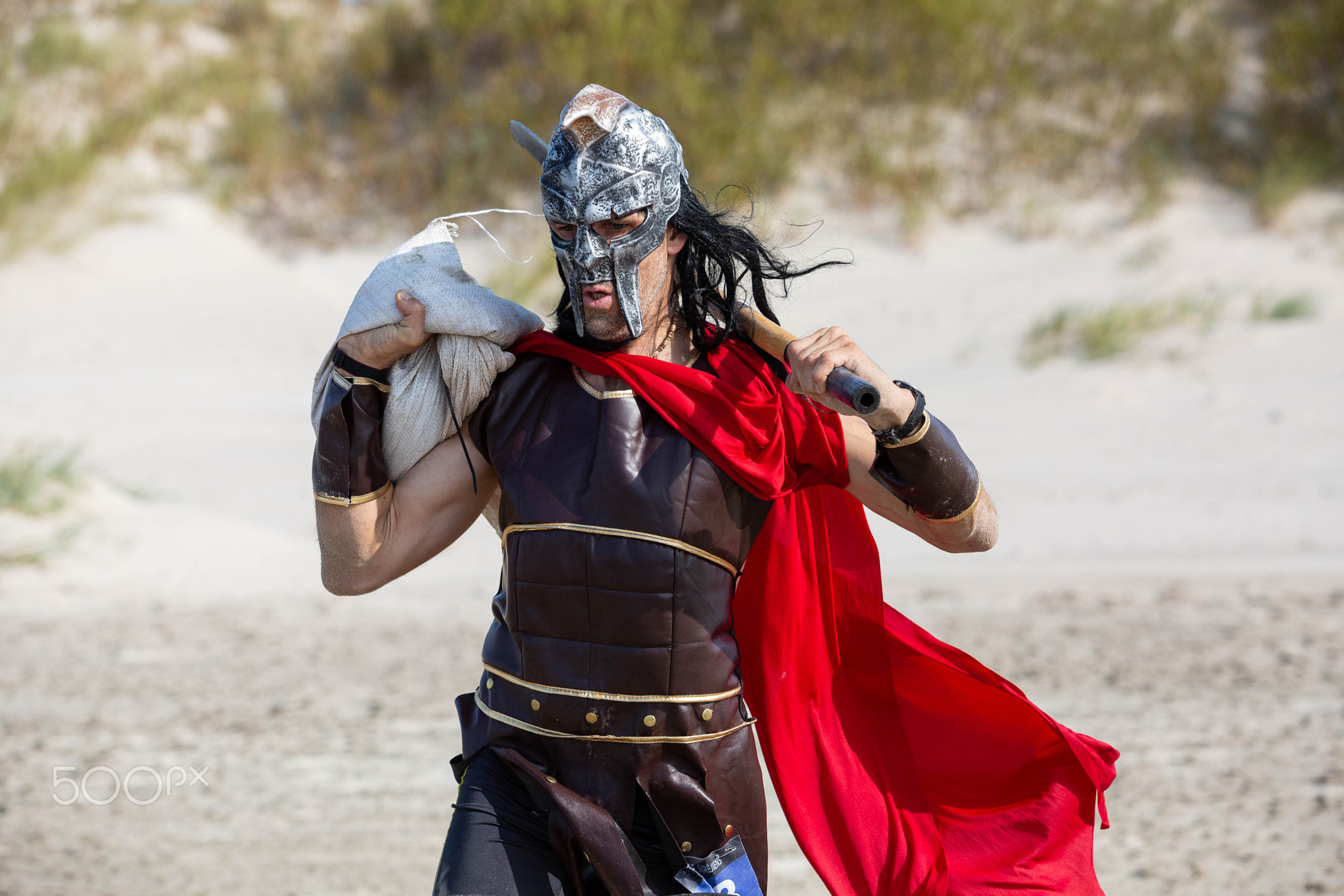 A Viking with a weapon in his hands runs along the sea shore.