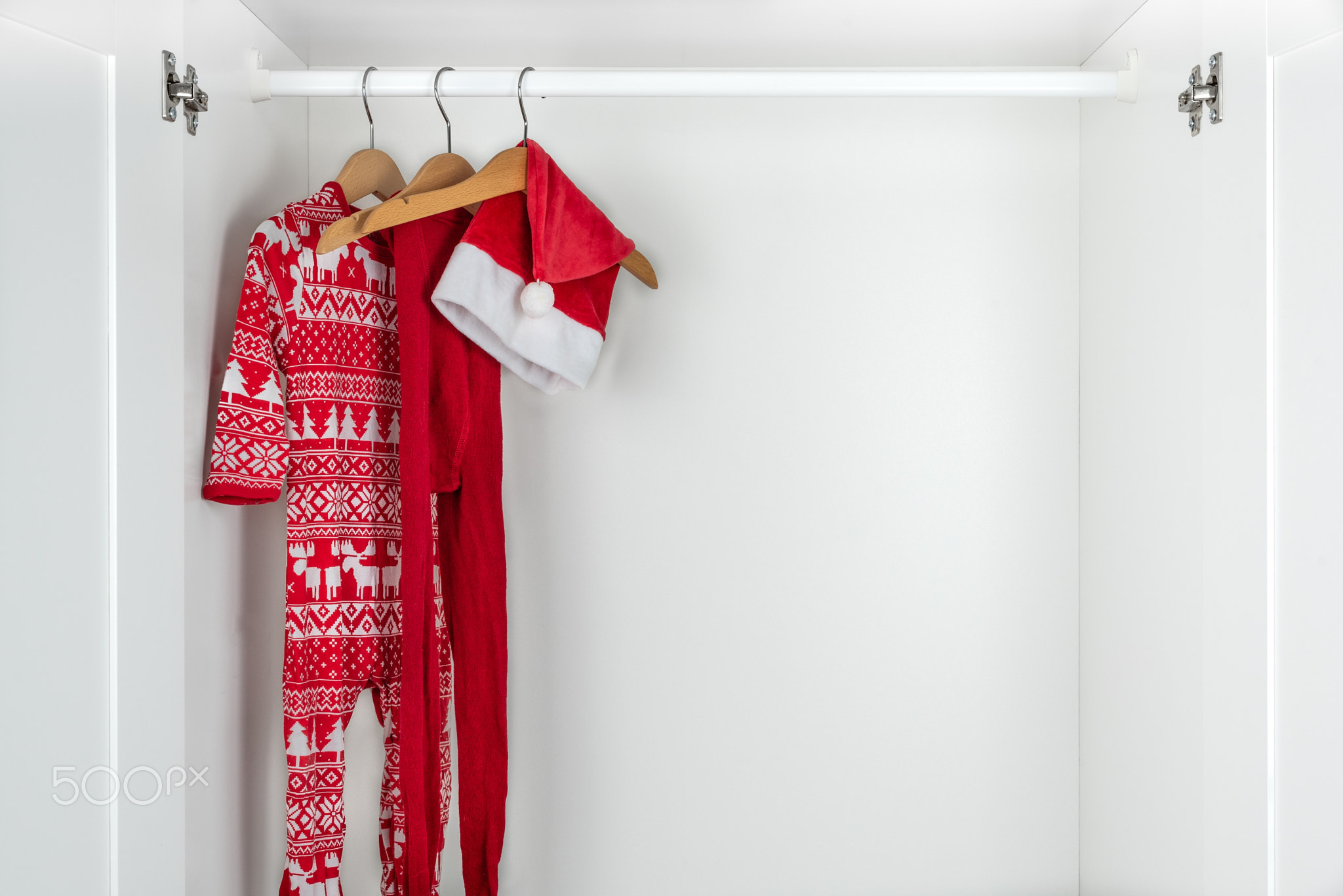 White and red christmas pajamas, hat and tights in a white closet.