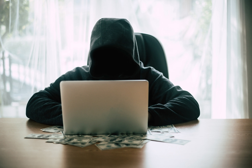 Hacker in front of his computer with dollar banknote. by Prakasit Khuansuwan on 500px.com