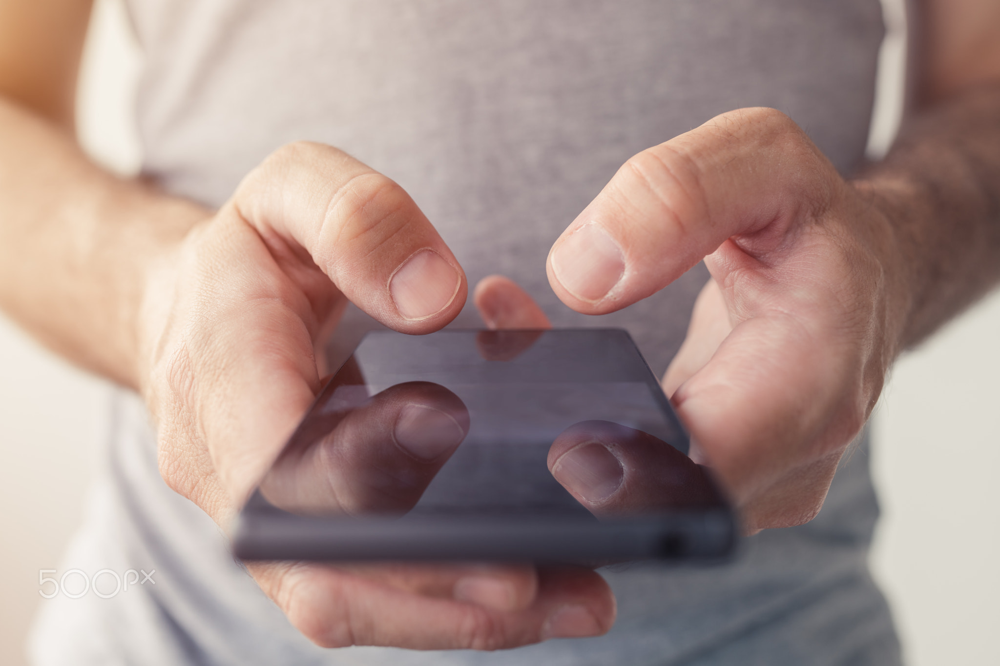 Close up of male hands typing text message on smartphone