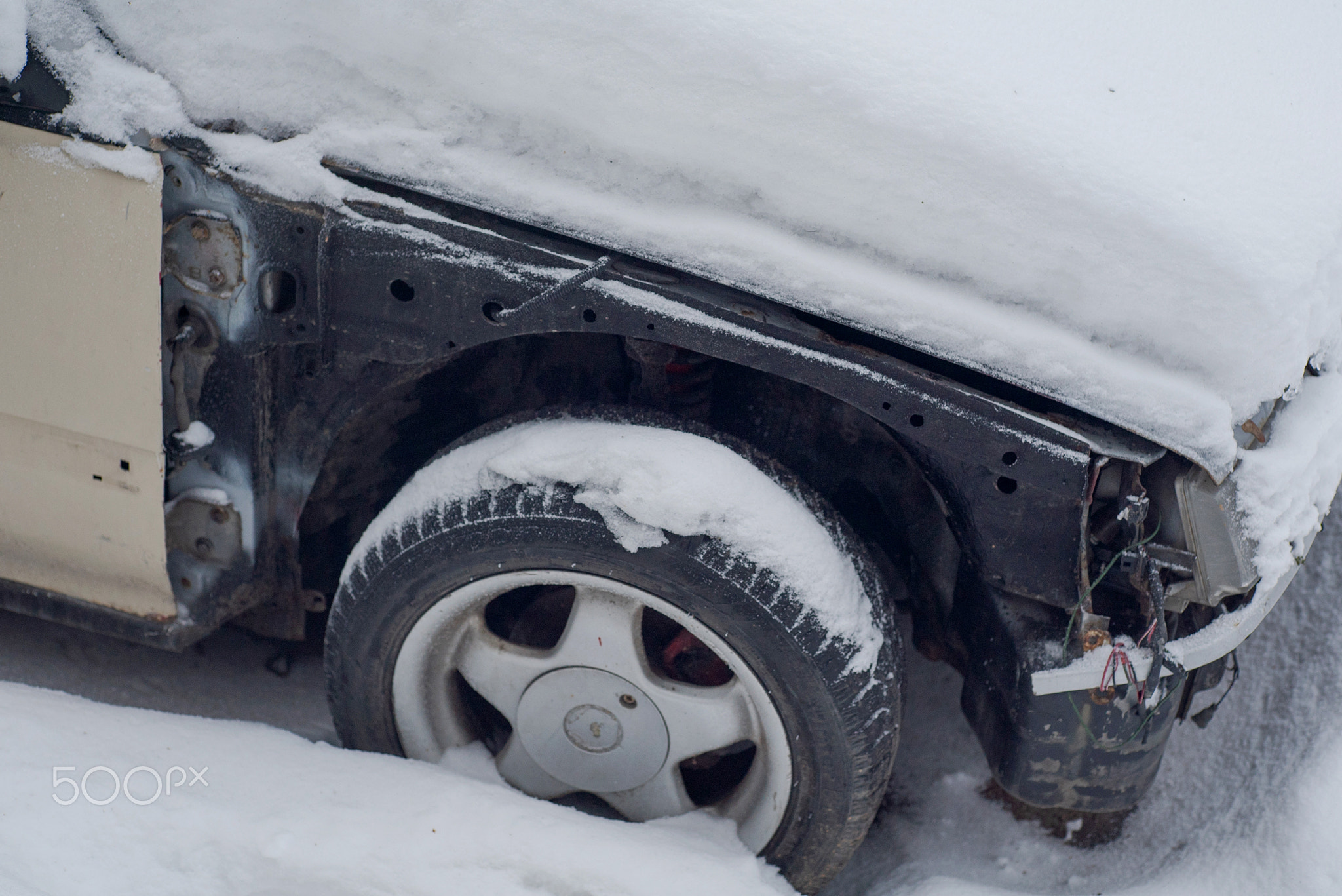Part of an old disassembled car in the snow.