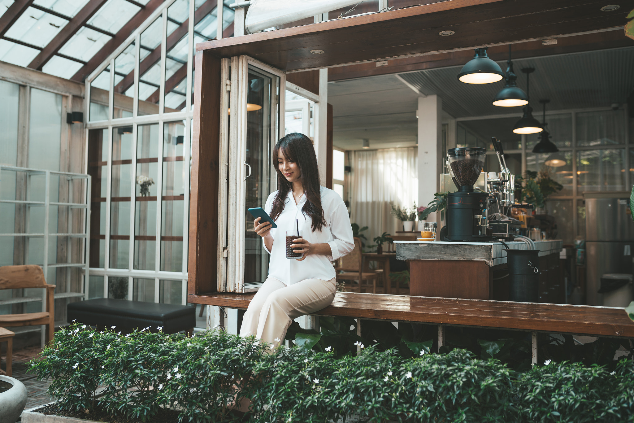 Cute asian young woman sitting in cafe with coffee and phone