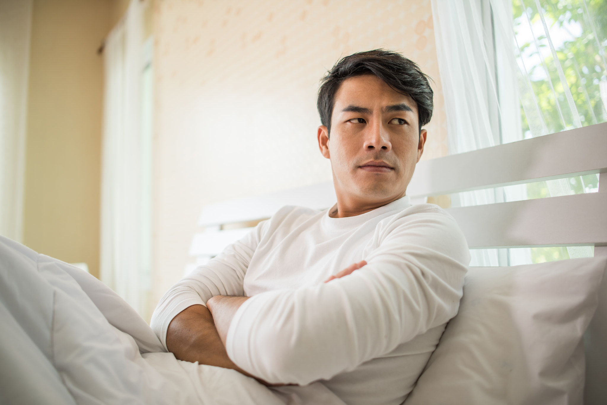 Upset man having problem sitting on the bed after arguing with.