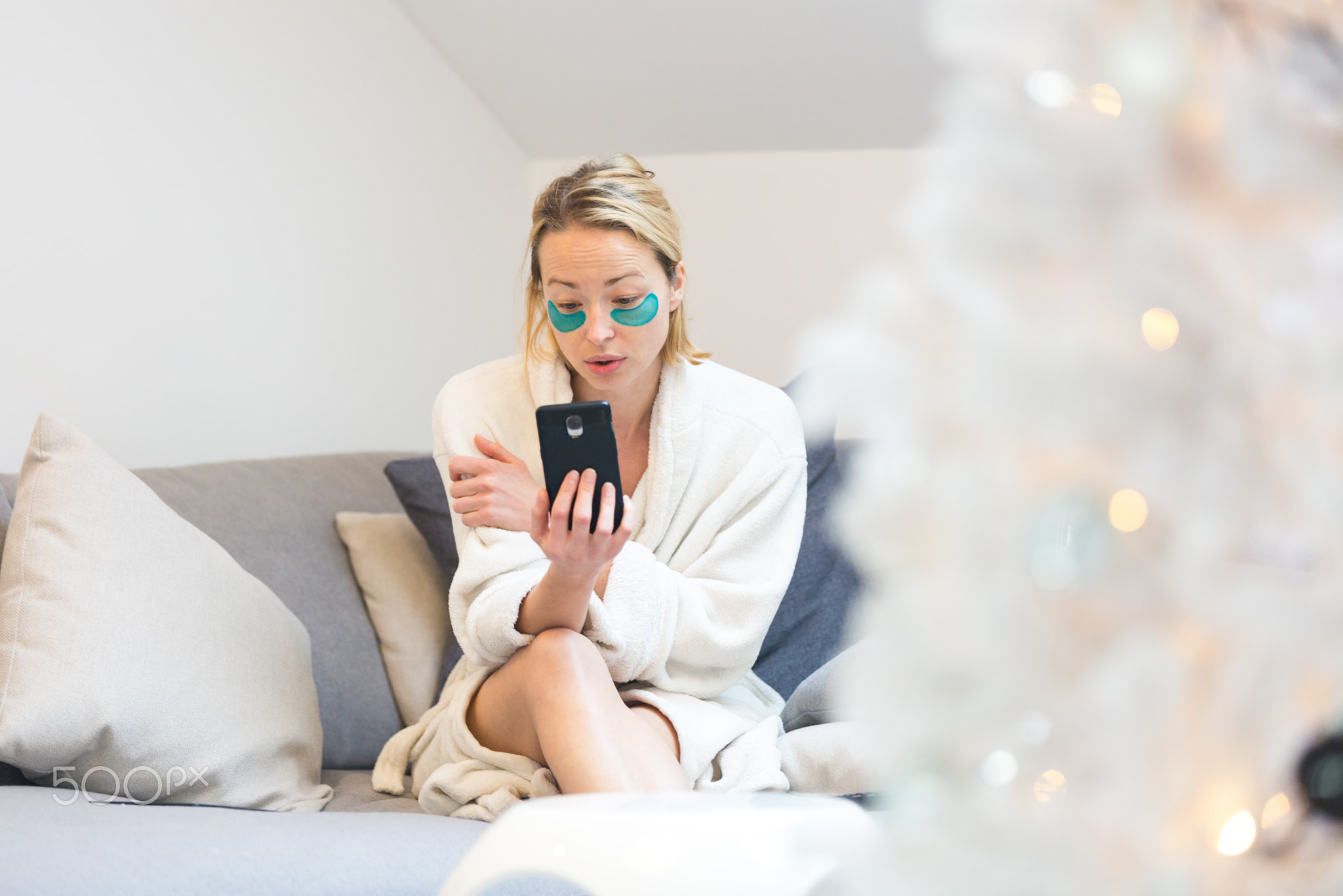 Woman at home relaxing on sofa couch using social media on phone for