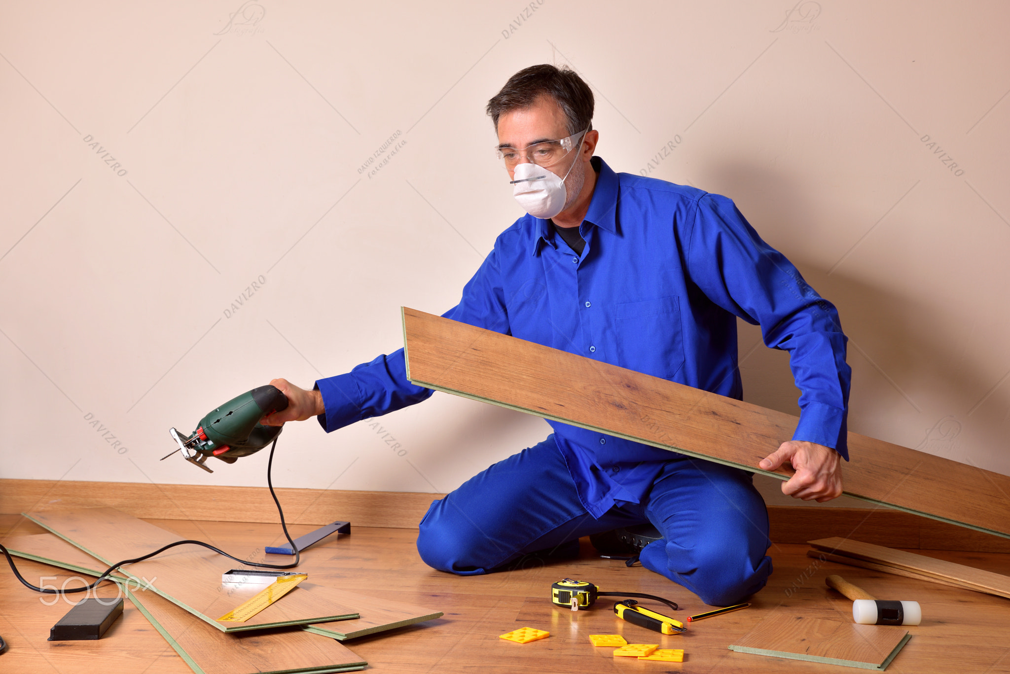 Professional parquet assembler with machine in hand assembling parquet