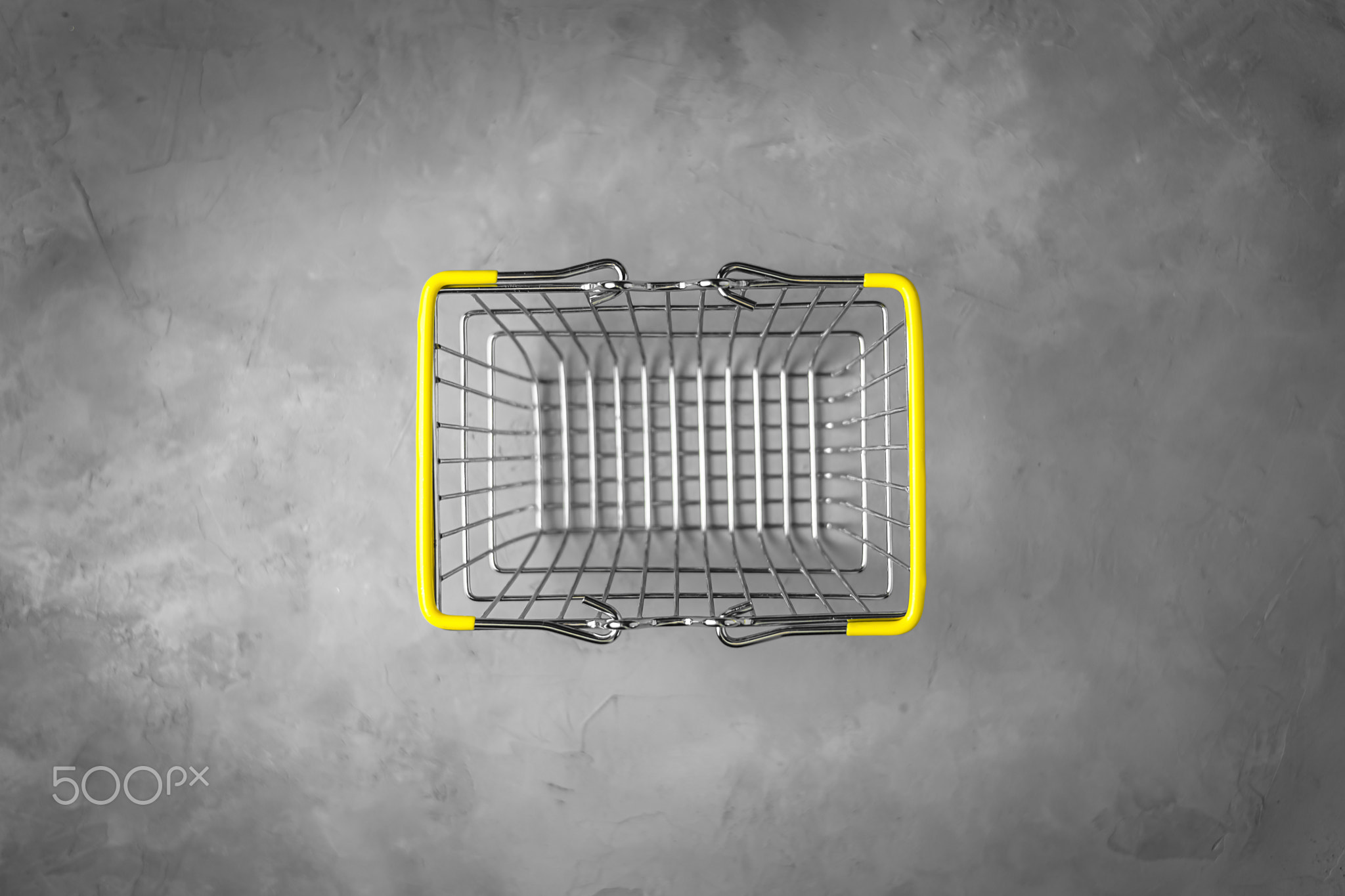 shopping basket with yellow handles on a gray background