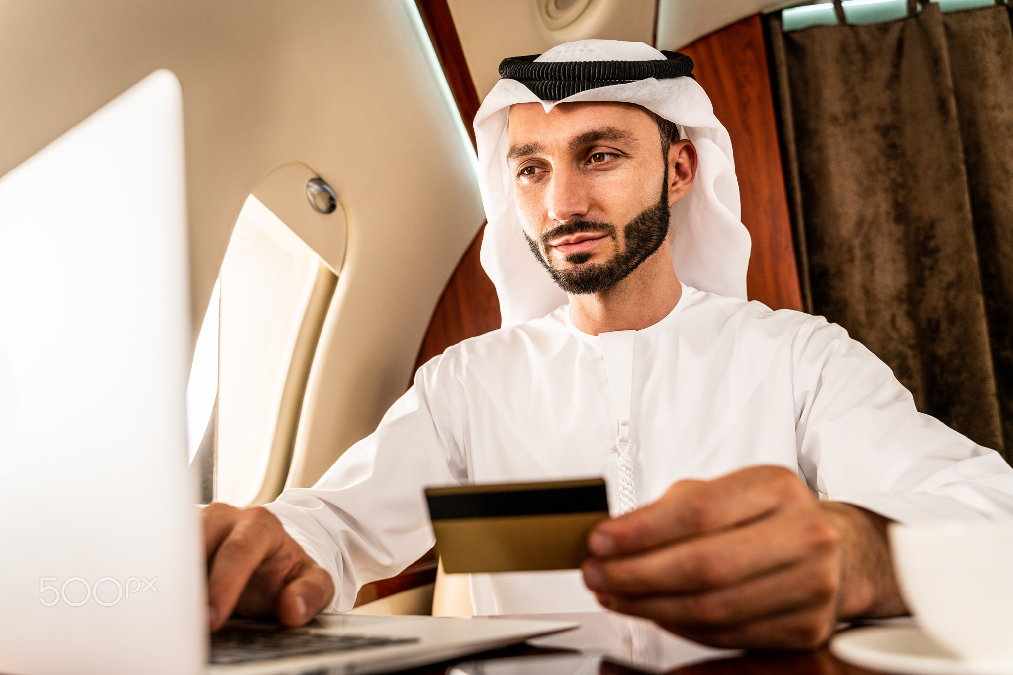 Arabian man wearing kandora flying on private jet