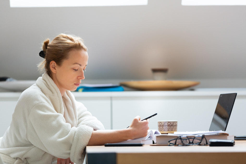 Young female entrepreneur wearing cosy warm bathrobe working remotly by Matej Kastelic on 500px.com