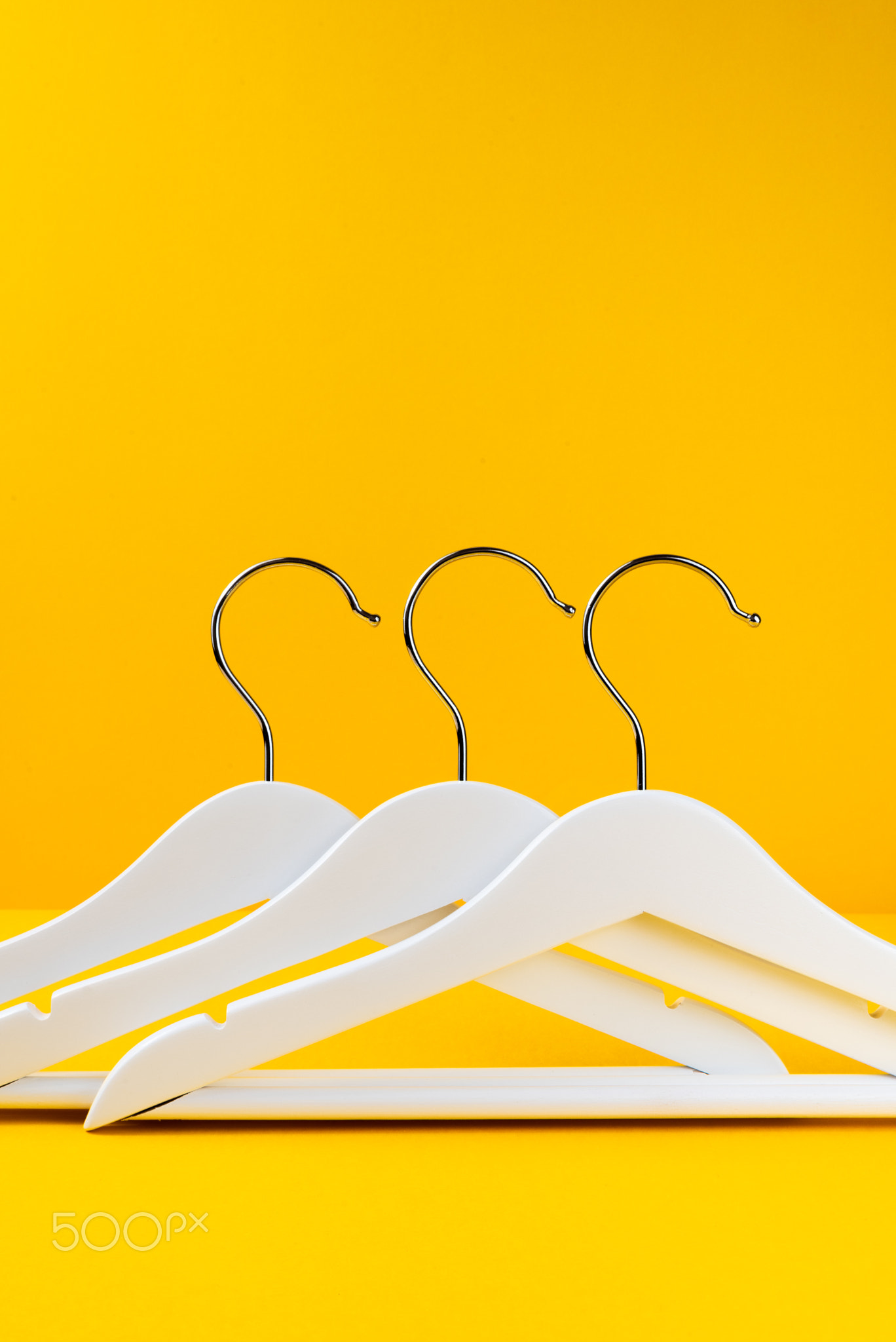 White hangers on a yellow background. Sales clothes concept.