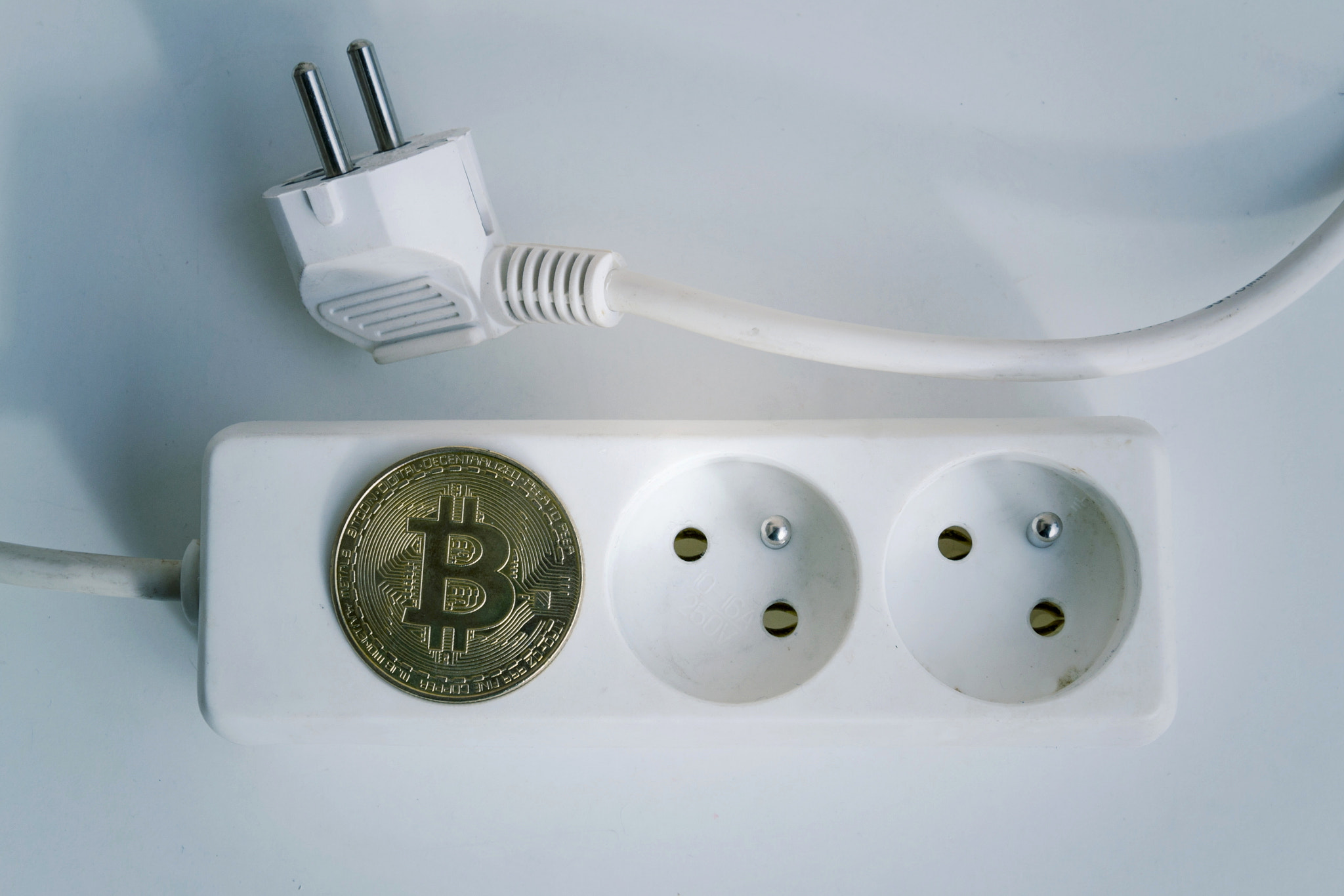 Bitcoin coin lying on power strip extension cord