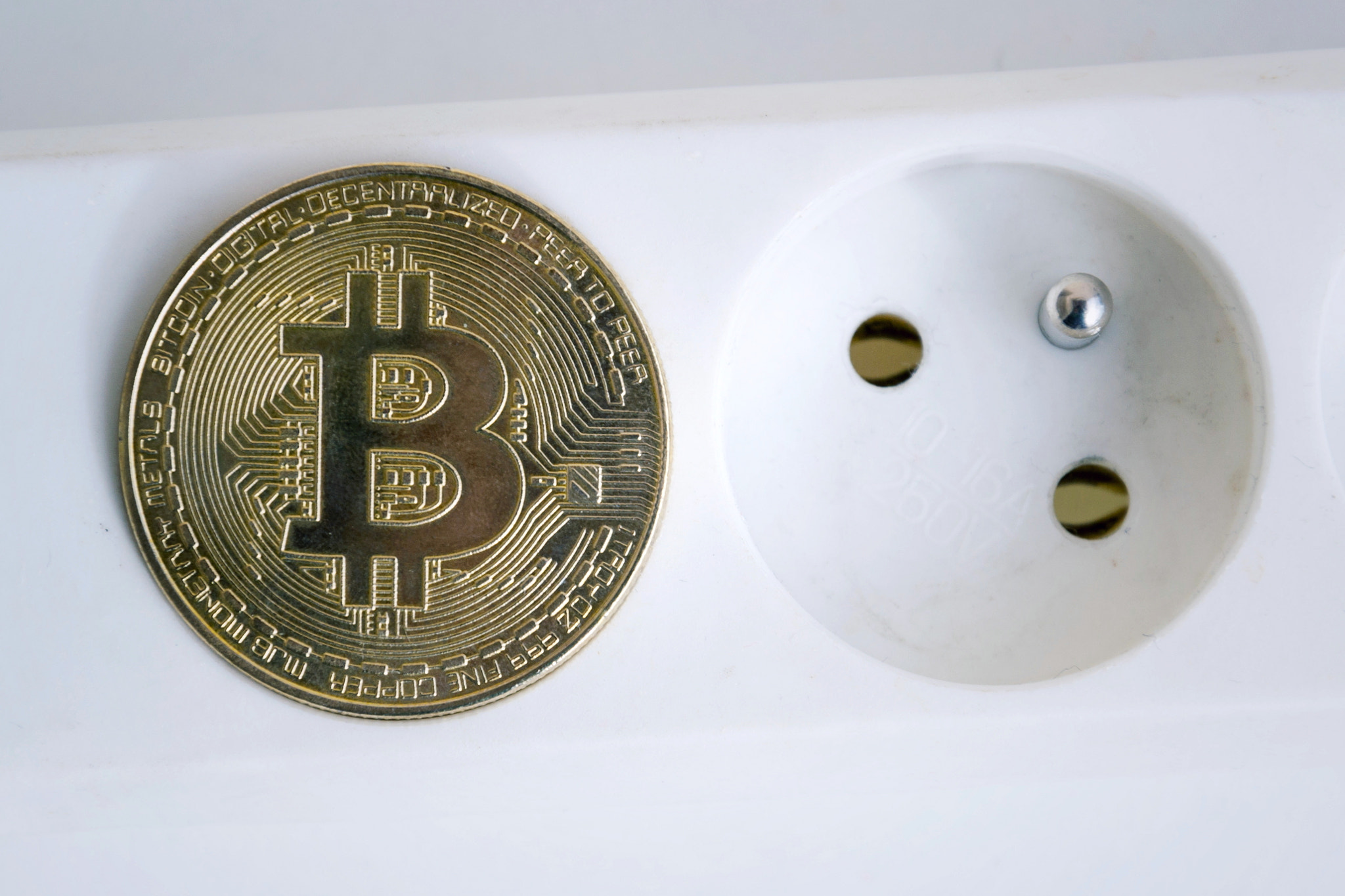 Bitcoin coin lying on power strip extension cord