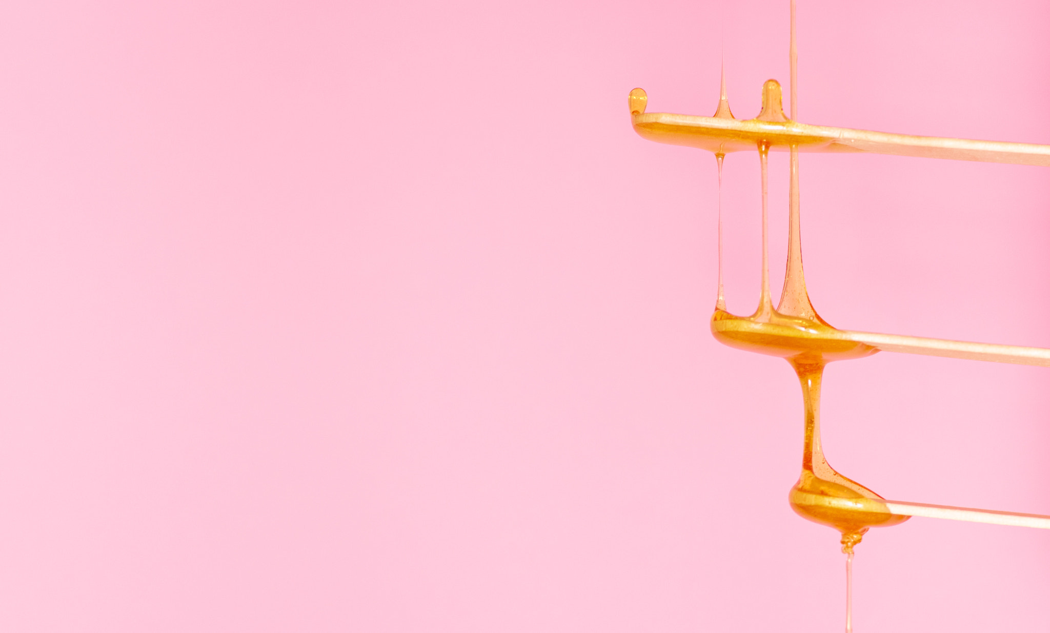 Sugar paste for hair removal runs down a wooden spatula. 