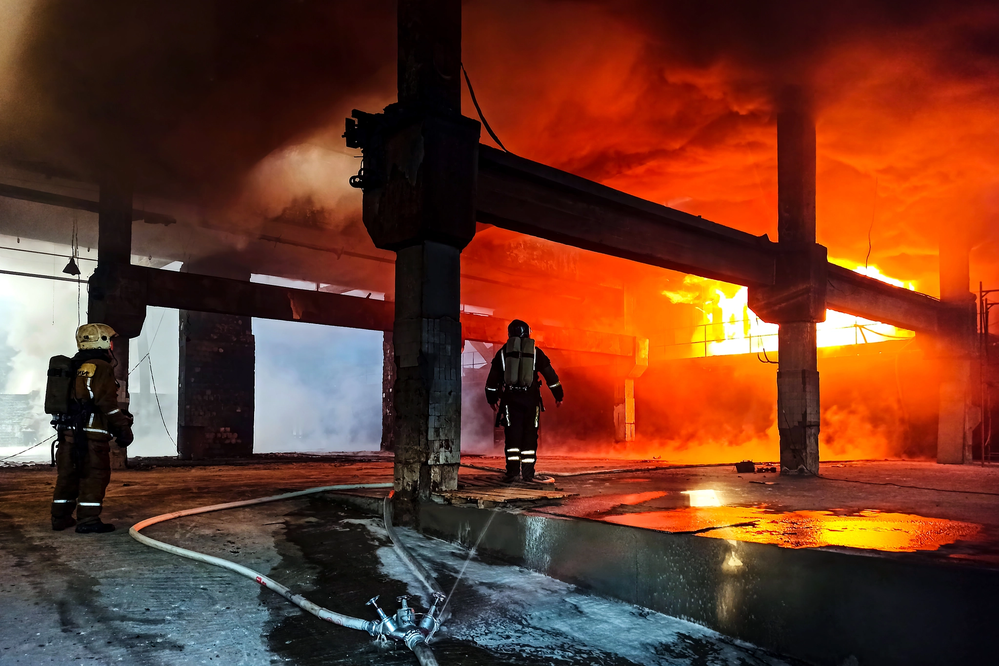 Firefighters in heat-resistant suits near an open fire.