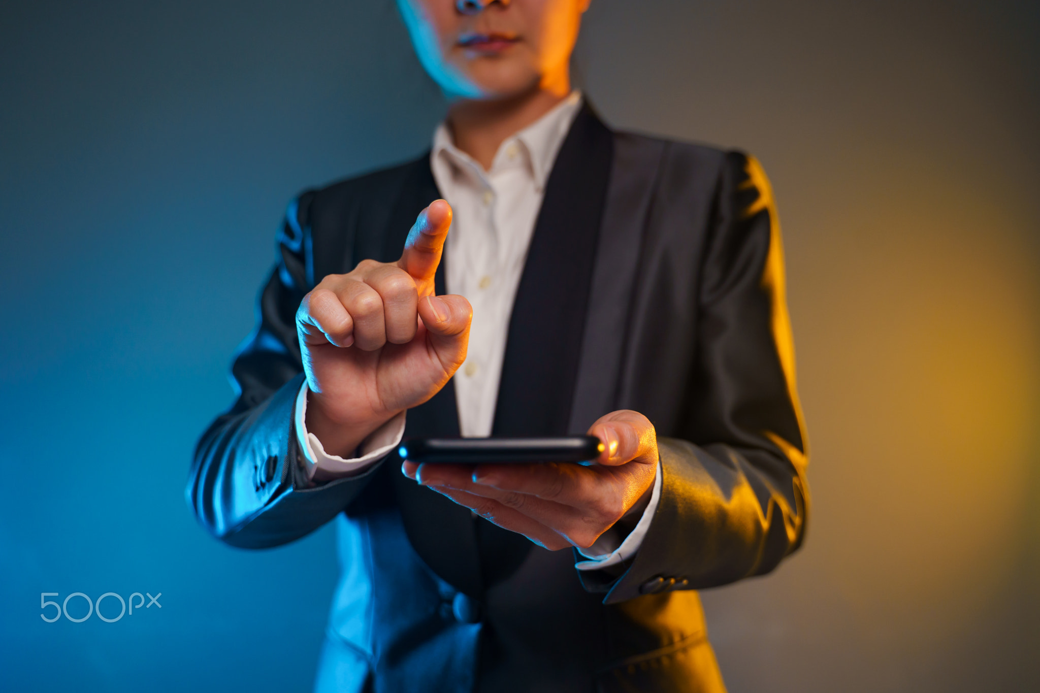 Business woman holding smart phone in black suit.