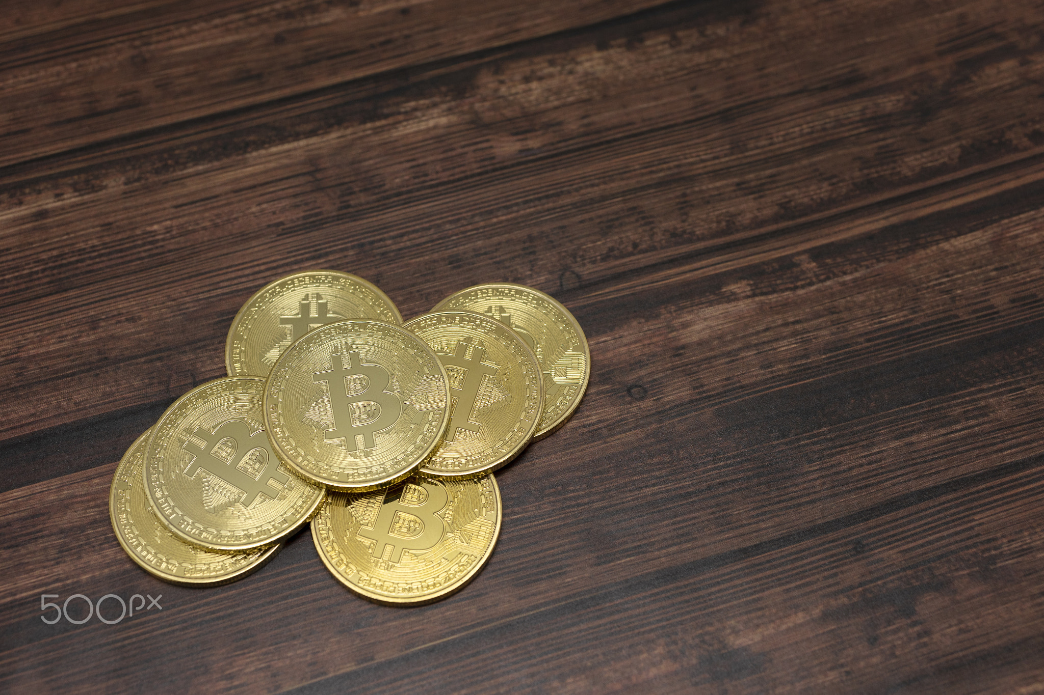 Virtual currency Golden Bitcoins on wood background.