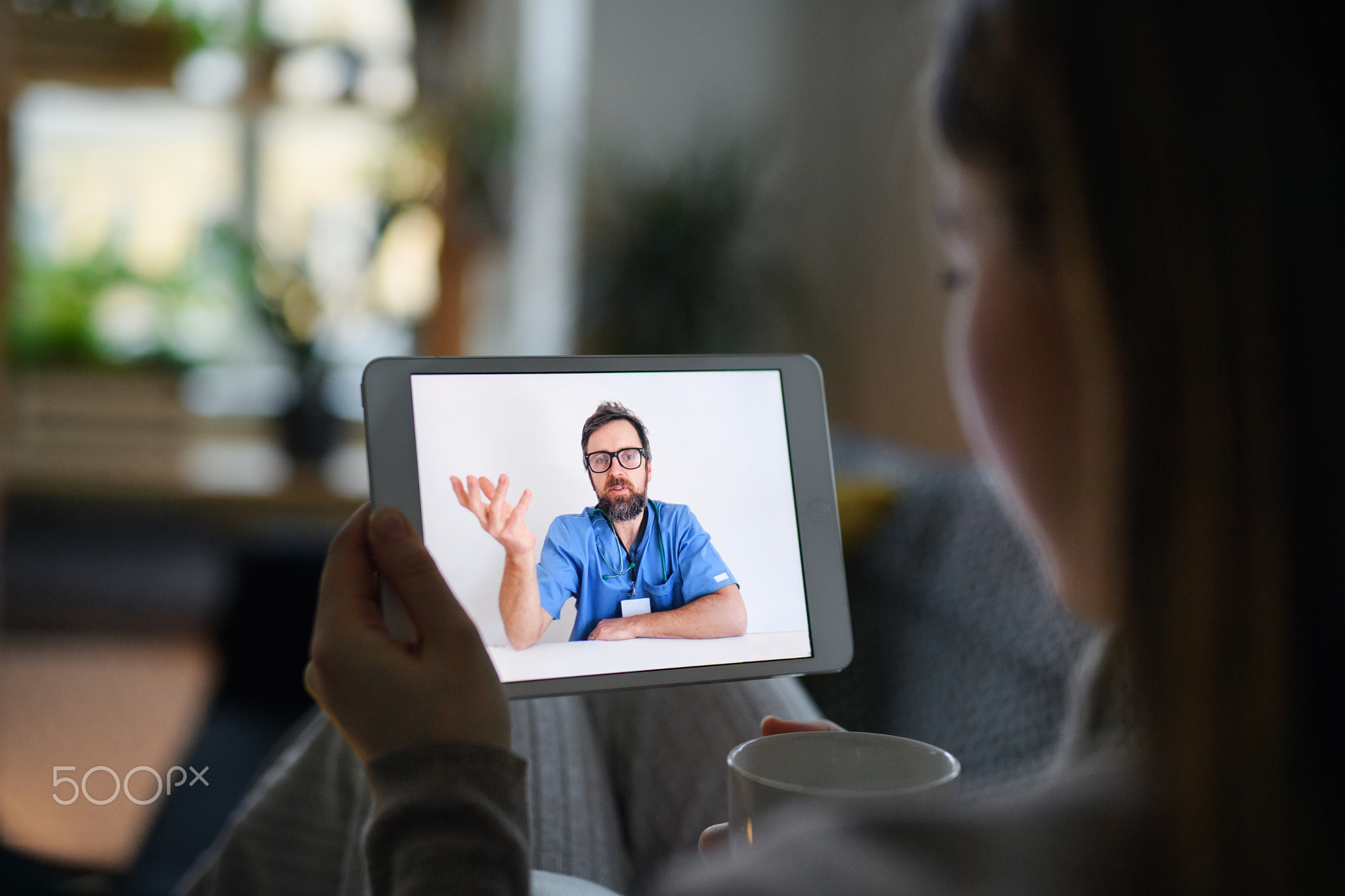 Young woman having video call with doctor on tablet at home, online