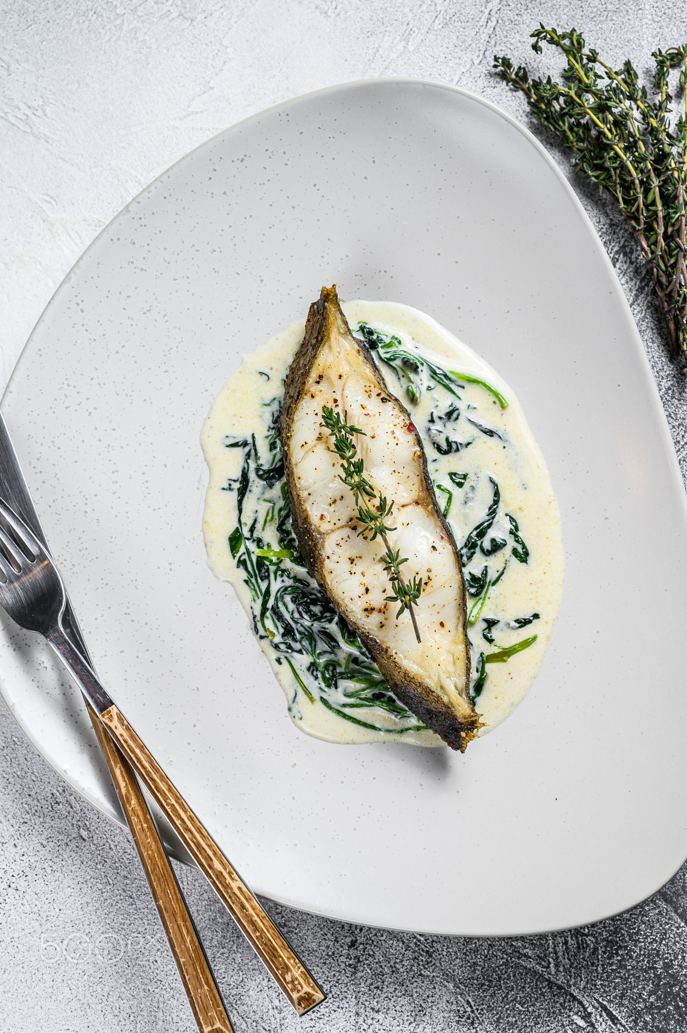 Baked Halibut fish steak with spinach. White background. Top view