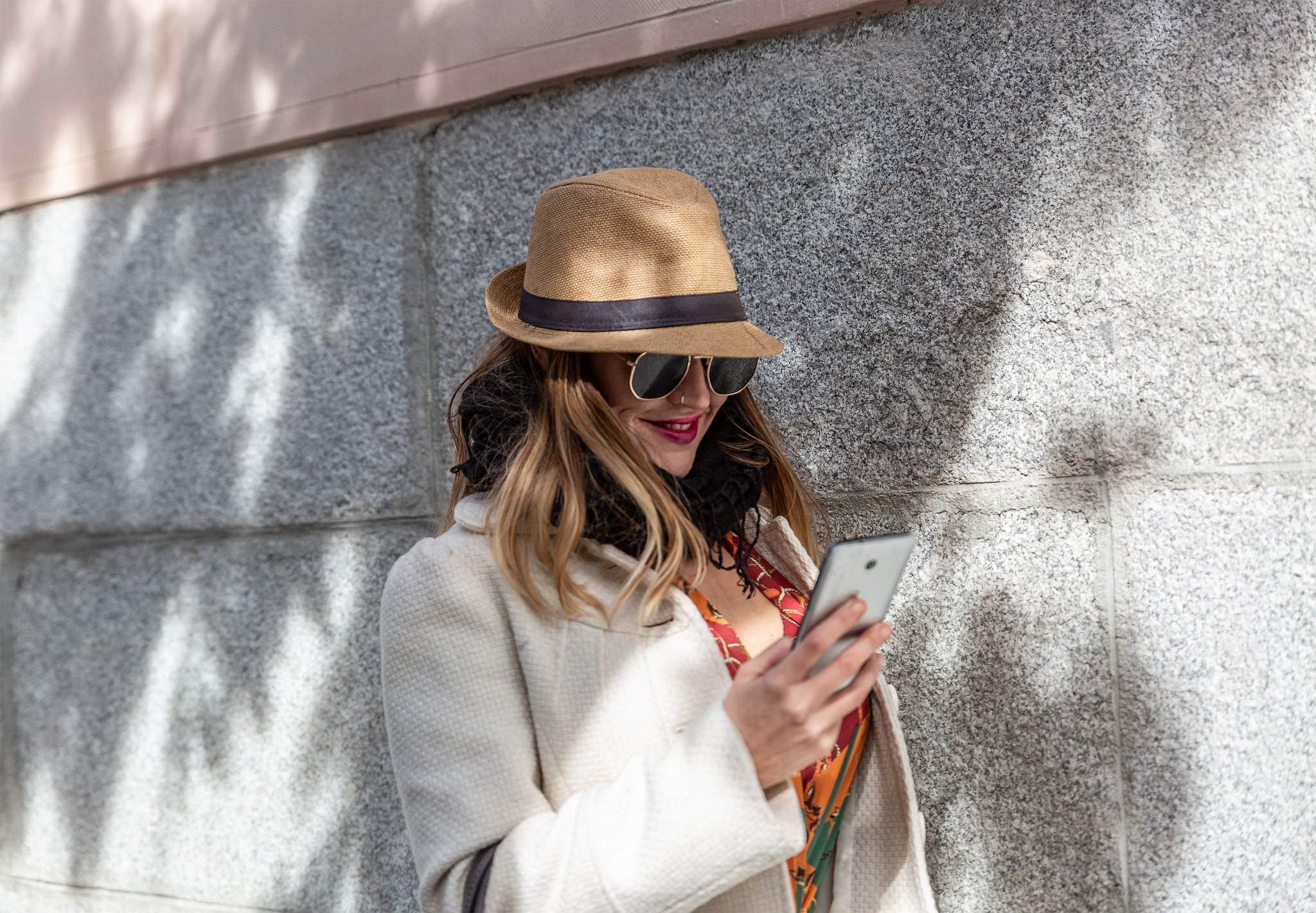 Attractive blonde with hat and black glasses looks smiling and happy