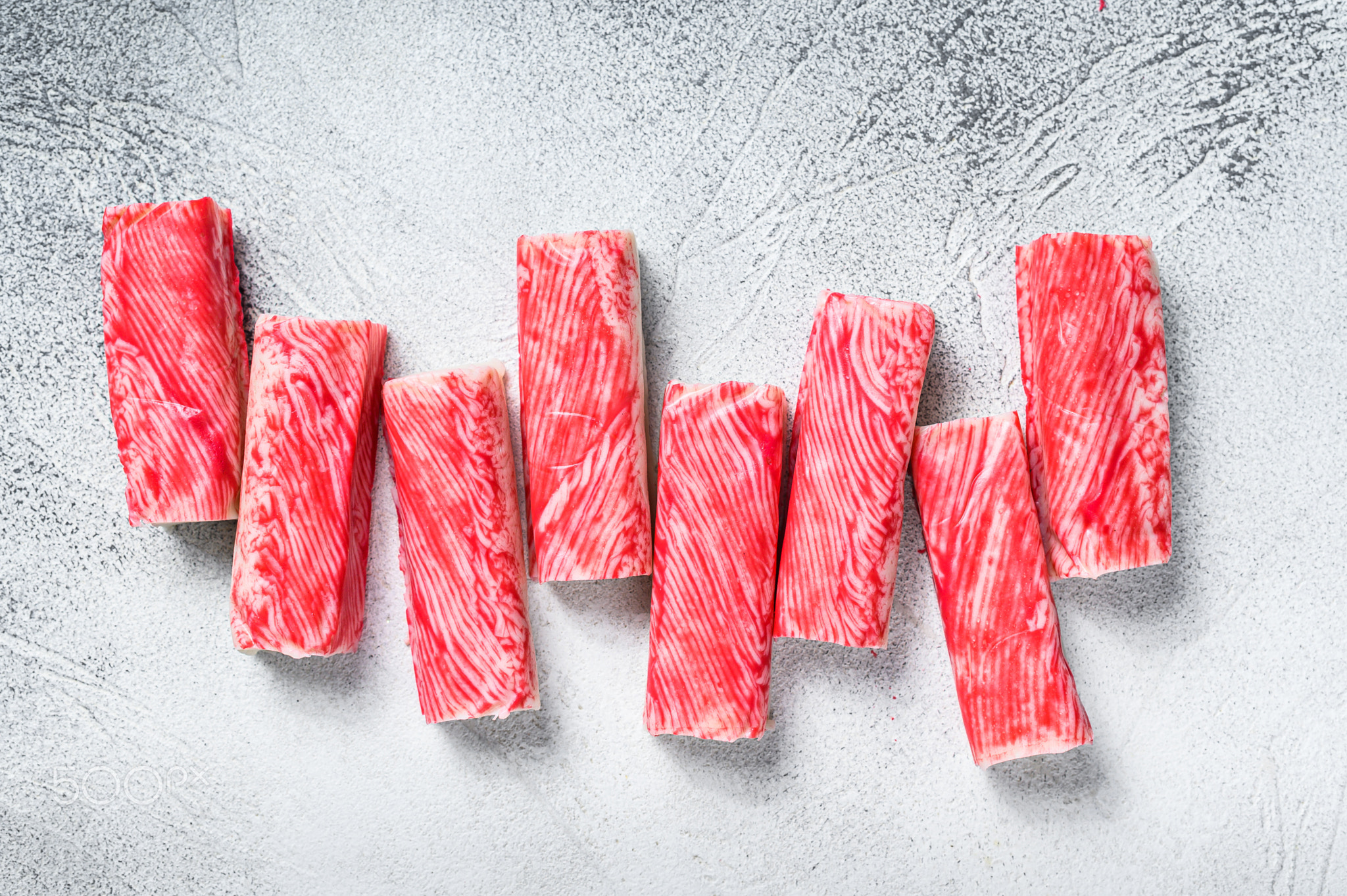 Crab surimi sticks on kitchen table. White background. Top view