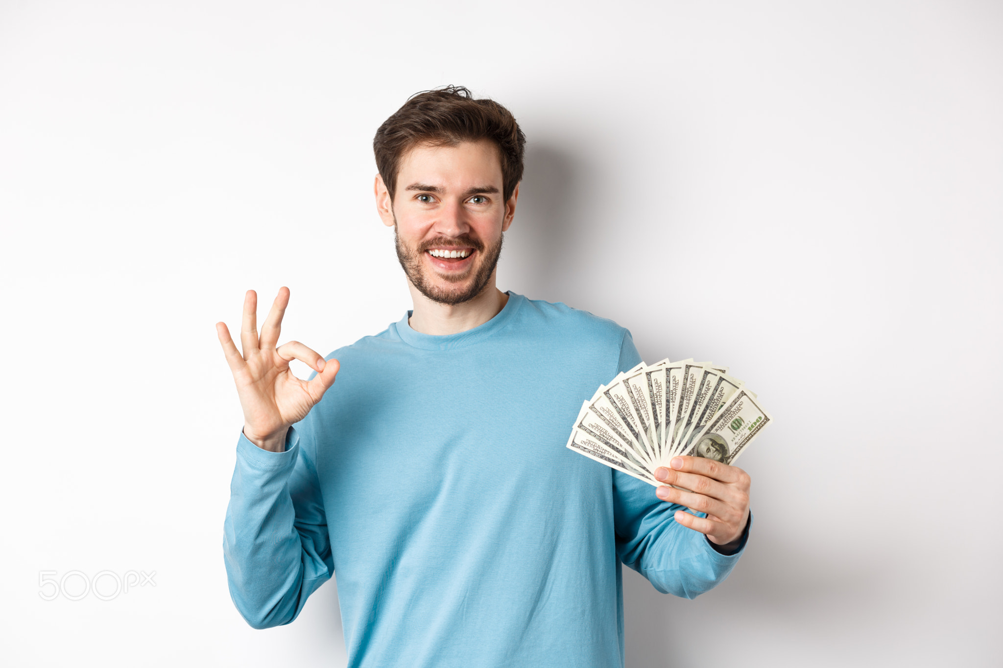 Handsome young man showing quick loans money, make okay gesture and