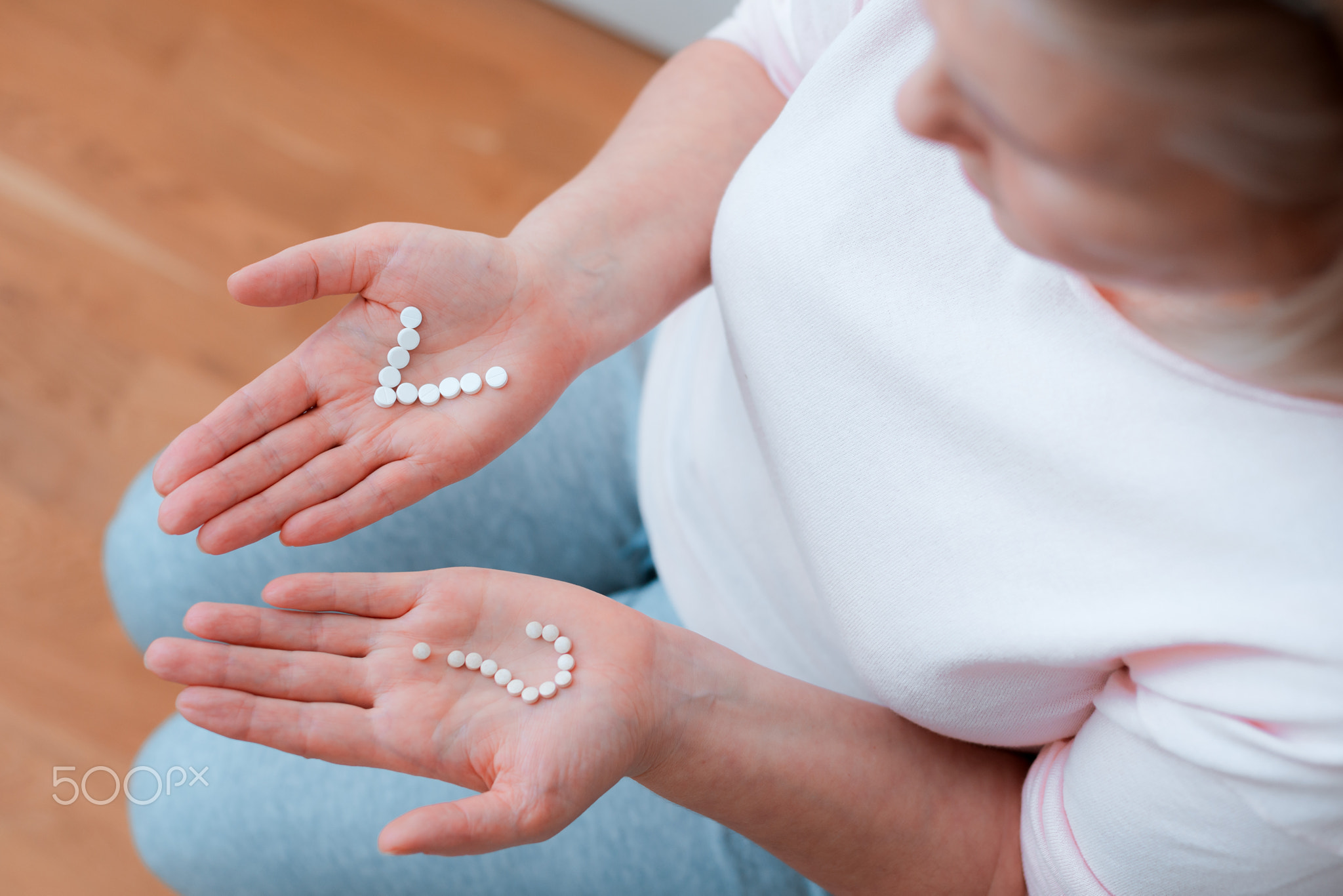 tablets and pills in the hands of a woman in the form of a question