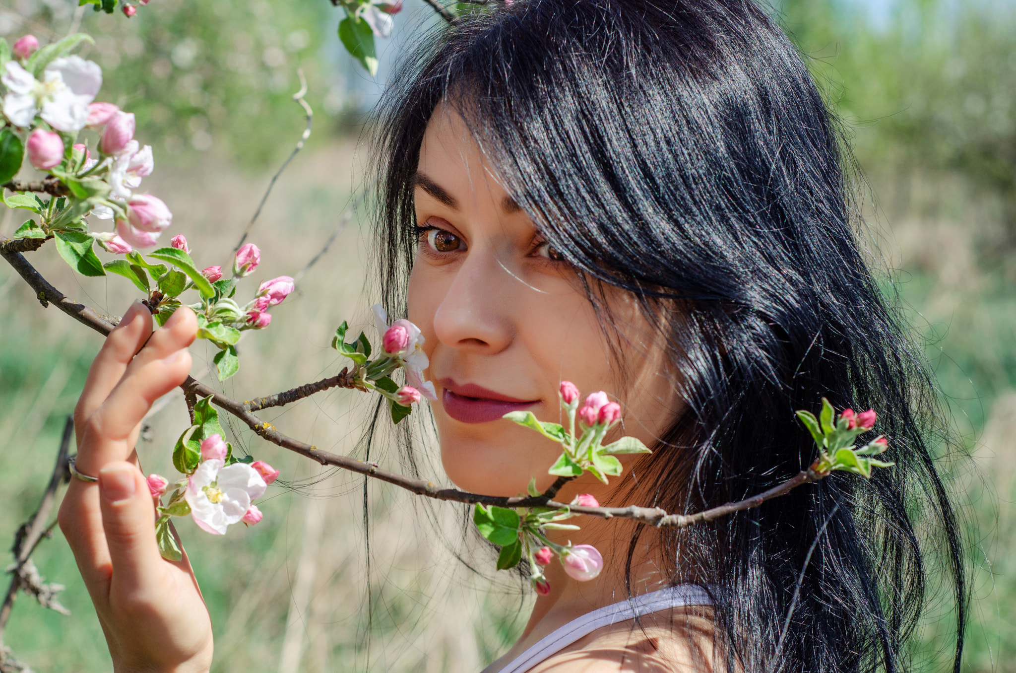 Nice girl in flowered garden, looking over her shoulder to the side