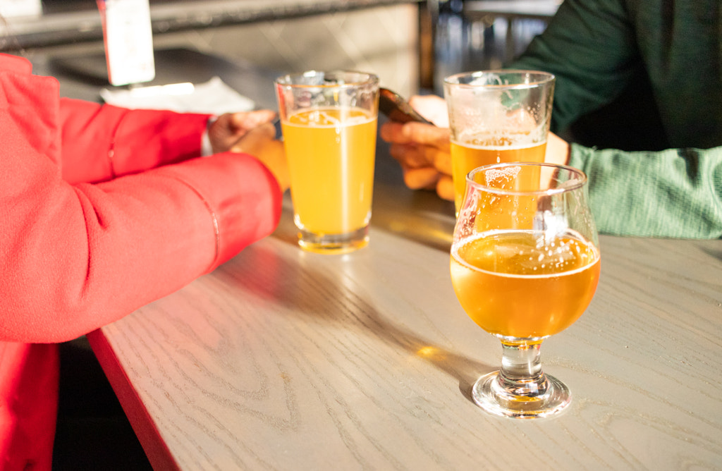 Friends celebrating with beers in a pub by Erik Gonzalez on 500px.com