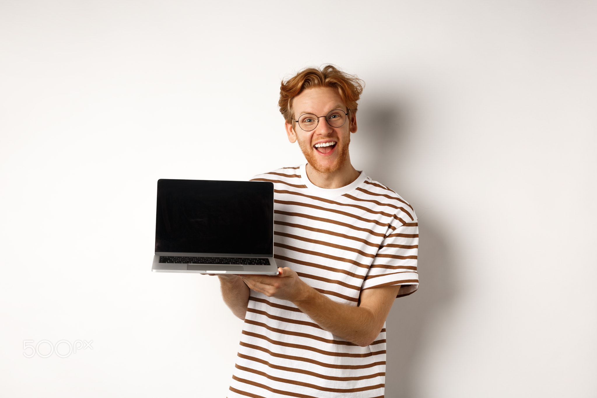 Funny redhead man in glasses showing laptop screen advertisement and