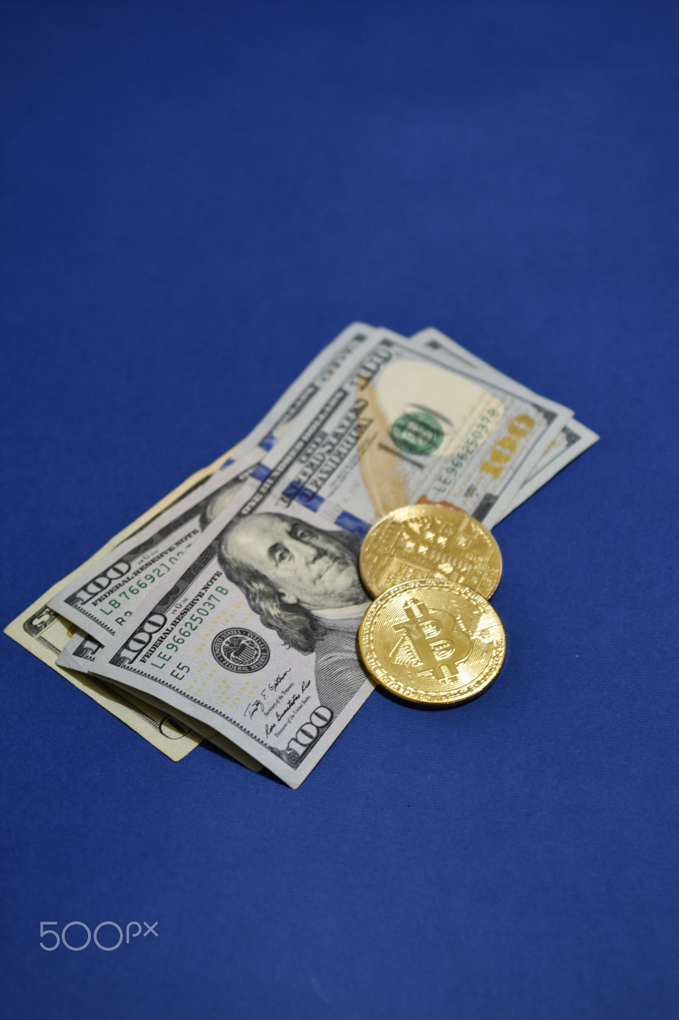Coins Bitcoin (BTC) on background of banknotes one hundred dollars .