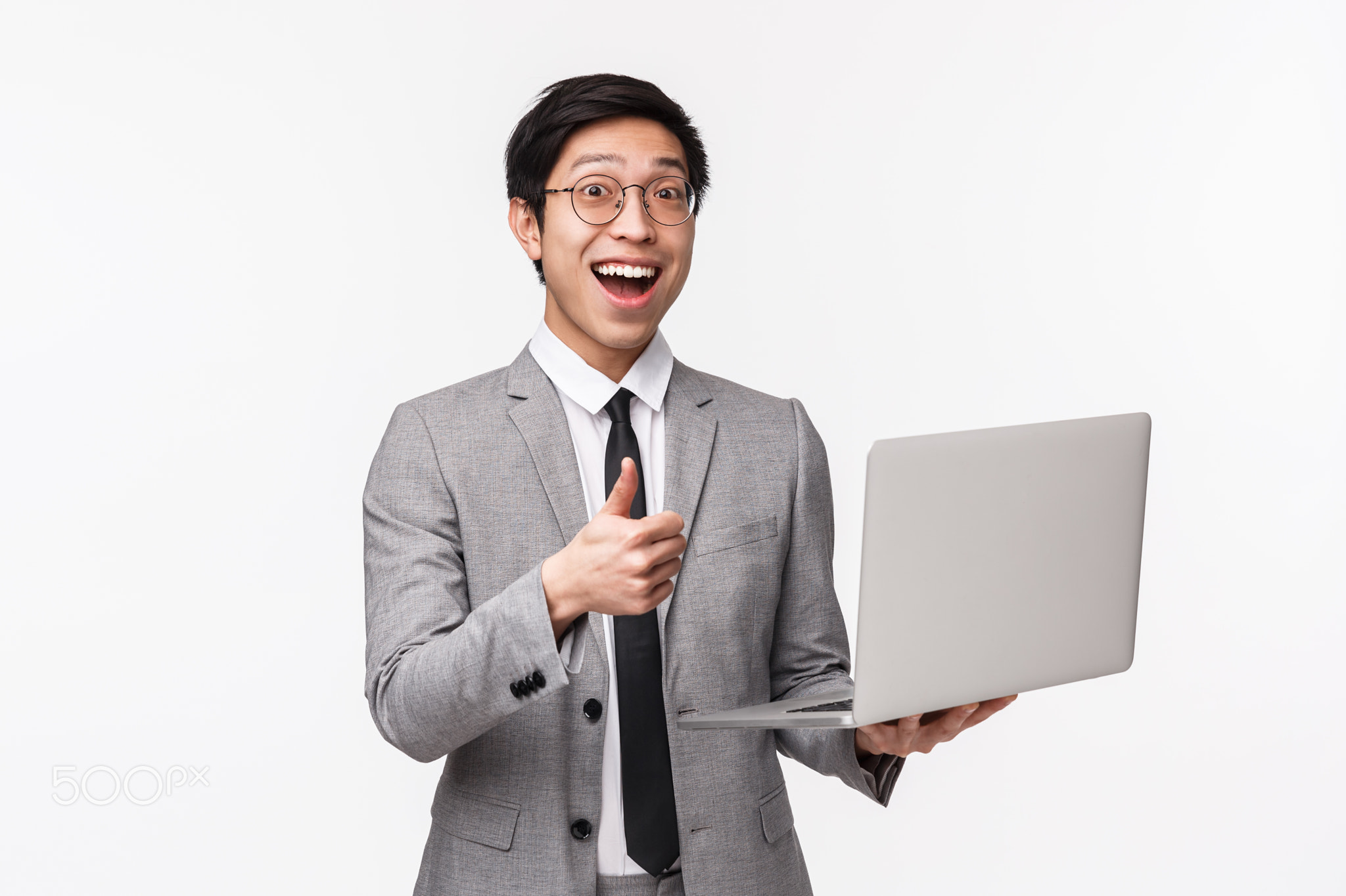 Waist-up portrait of enthusiastic happy young asian man in grey suit