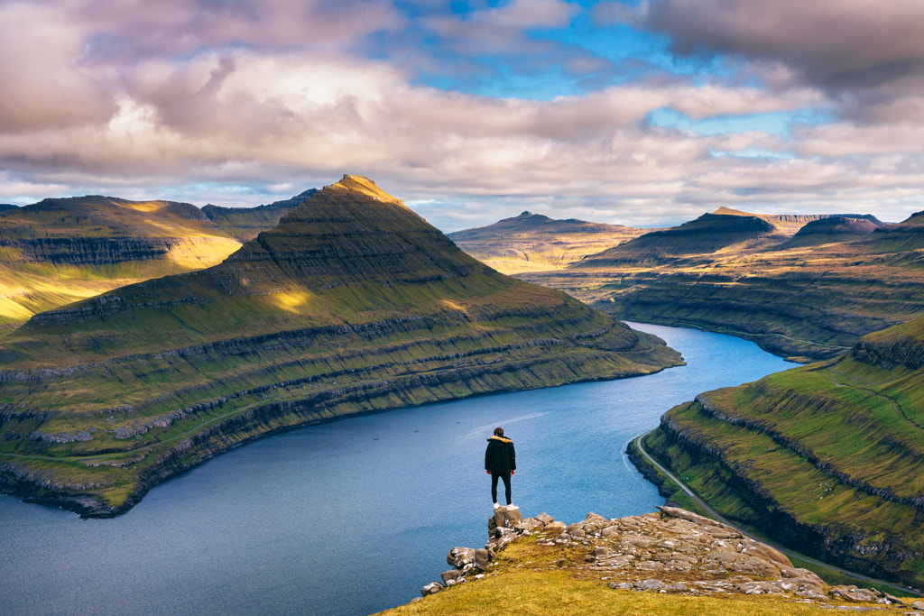 Hiker enjoys views over fjords from a mountain near Funningur on Faroe ...