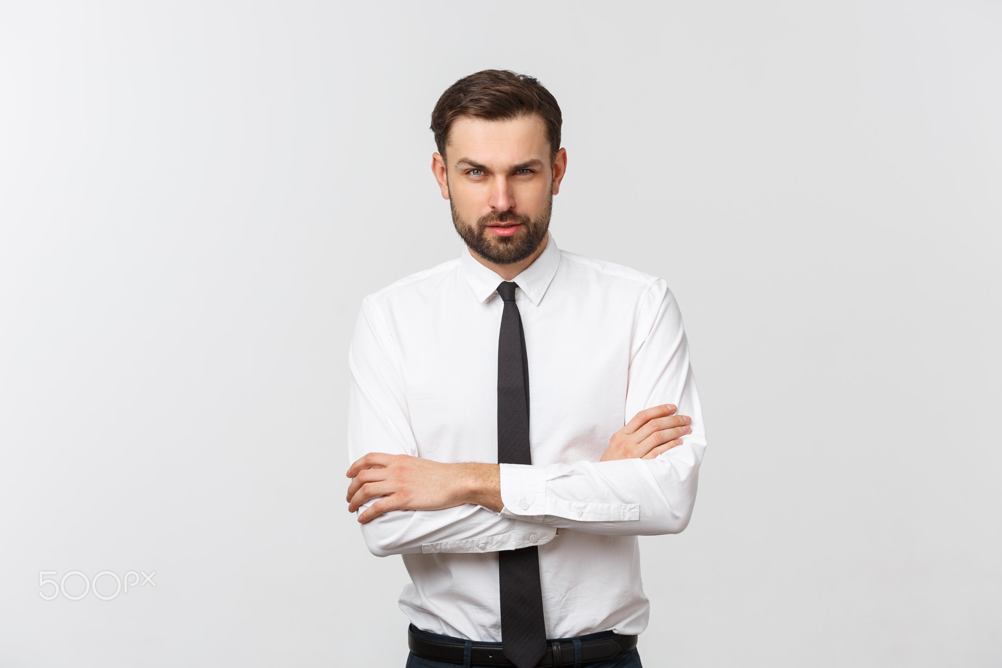 Portrait of a confident young businessman with crossing arms on white