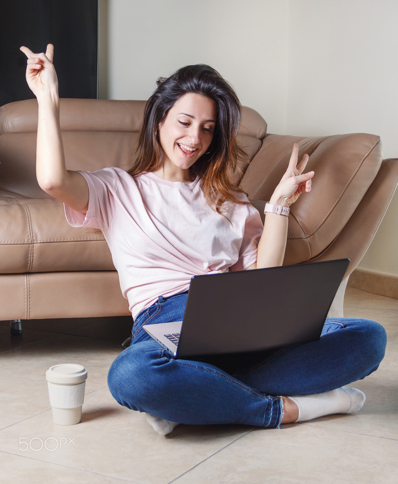 Young women with laptop show victoria gesture with fingers and smile
