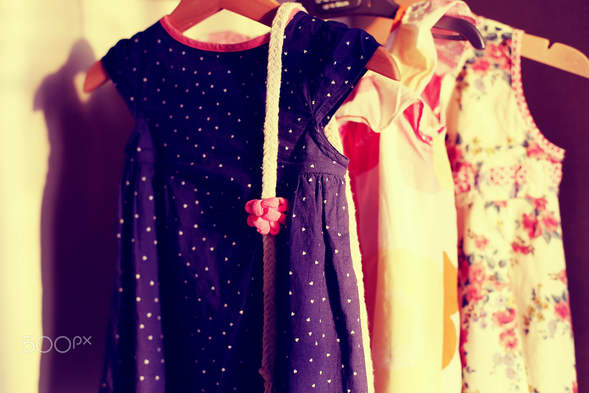 Closet with colorful baby dresses on hangers