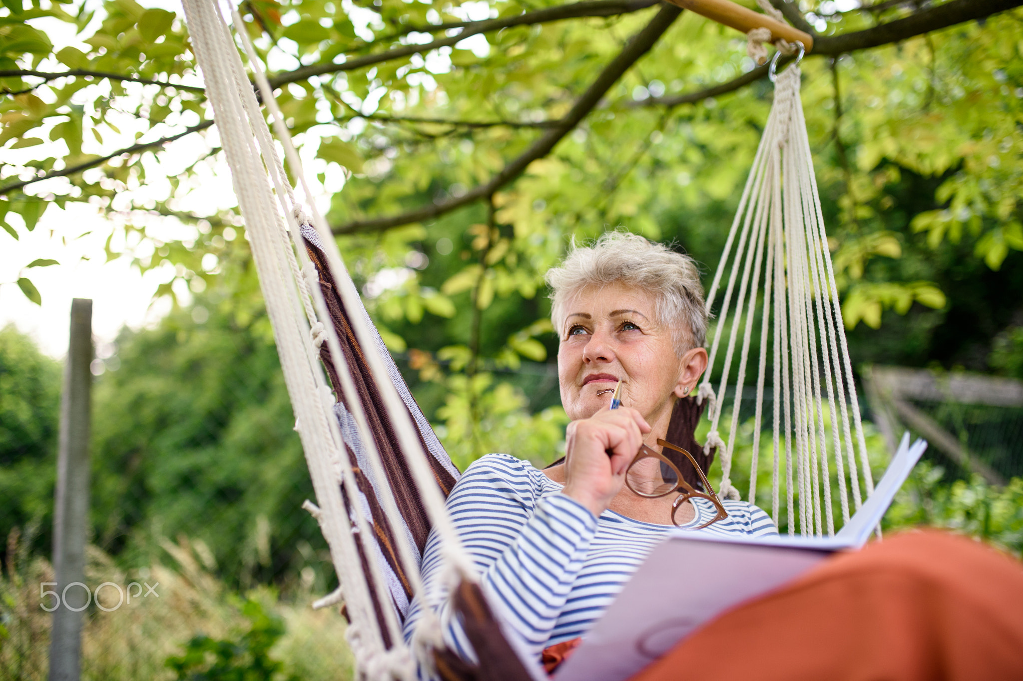 Portrait of happy senior woman sitting outdoors on hanging swing chair