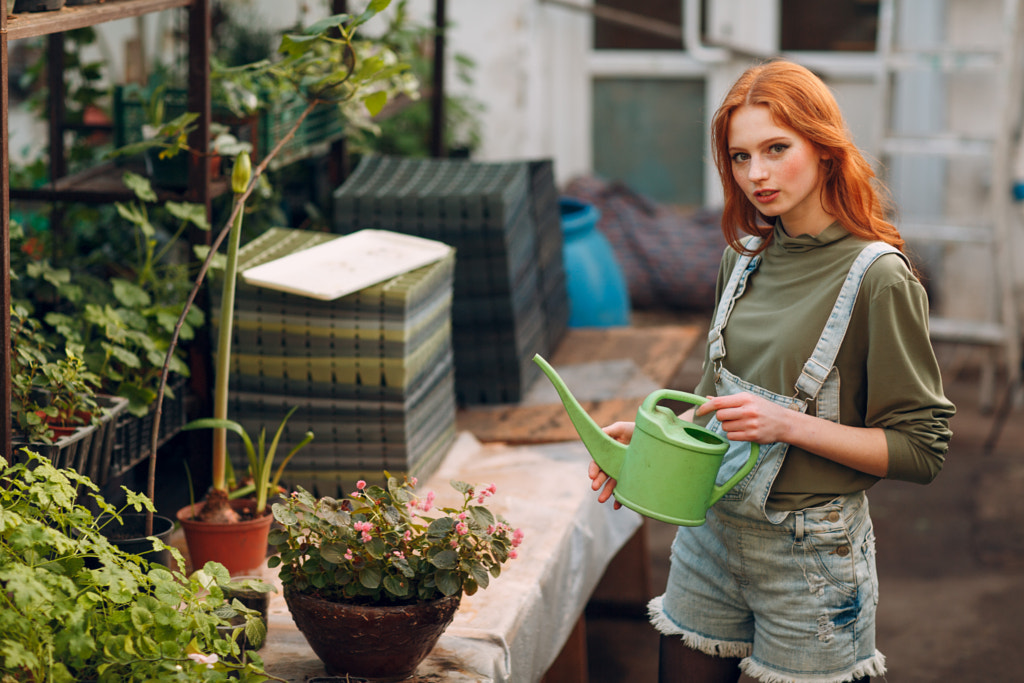 Home gardening concept. Young ginger girl with watering can plants by Max Chernishev on 500px.com