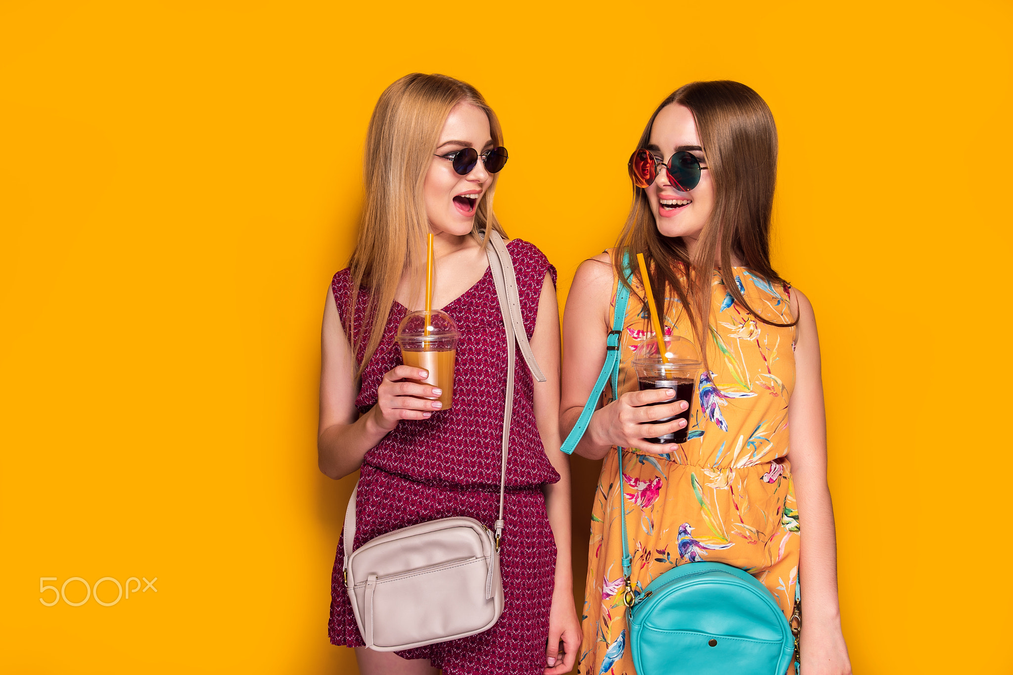 Two cheerful young women girls friends in summer clothes with bags