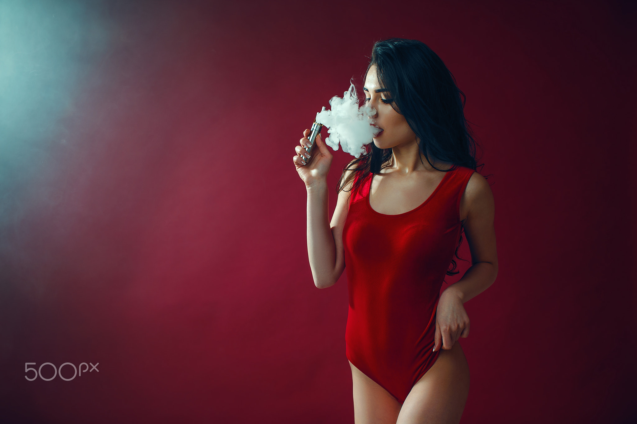 Young sexy woman in red body is vaping.