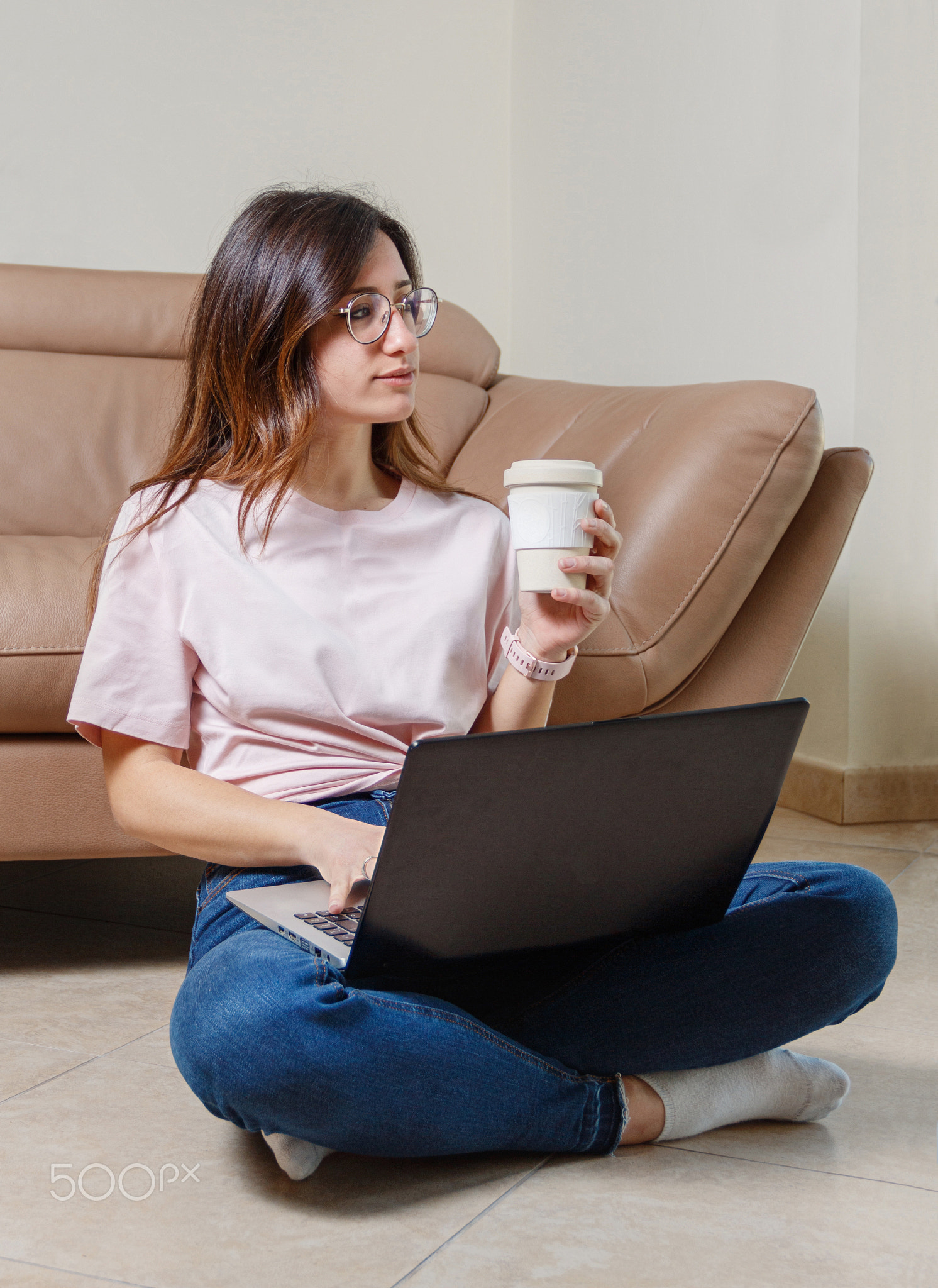Young women working with laptop while sitting on the floor at home