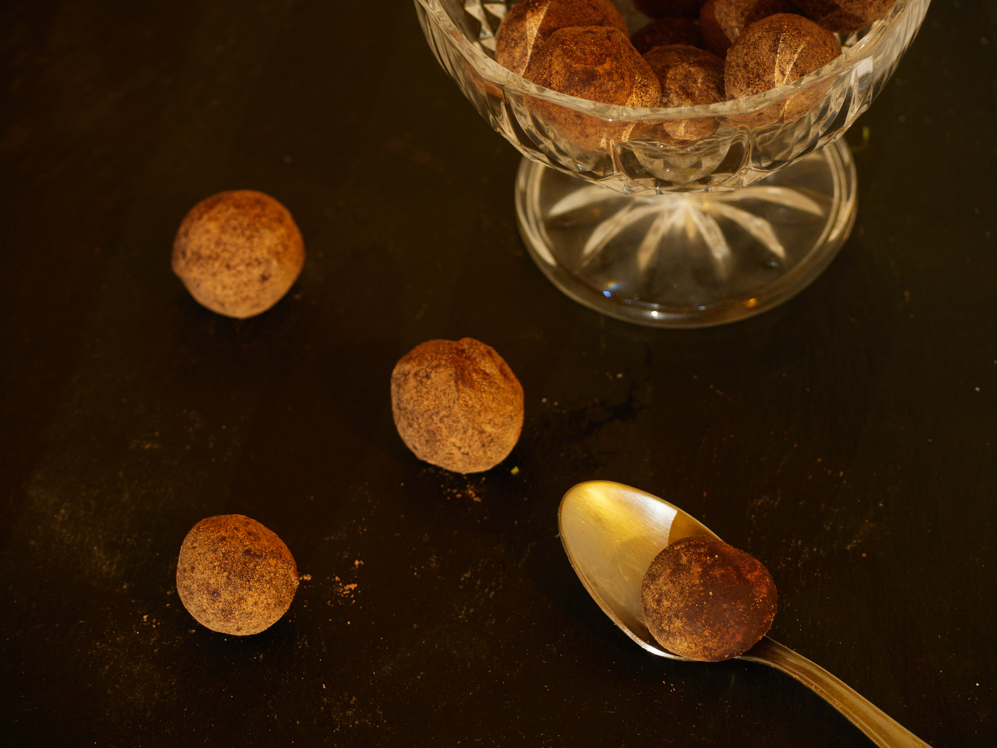 Several Chocolate Truffles with cocoa powder with a spoon and a glass