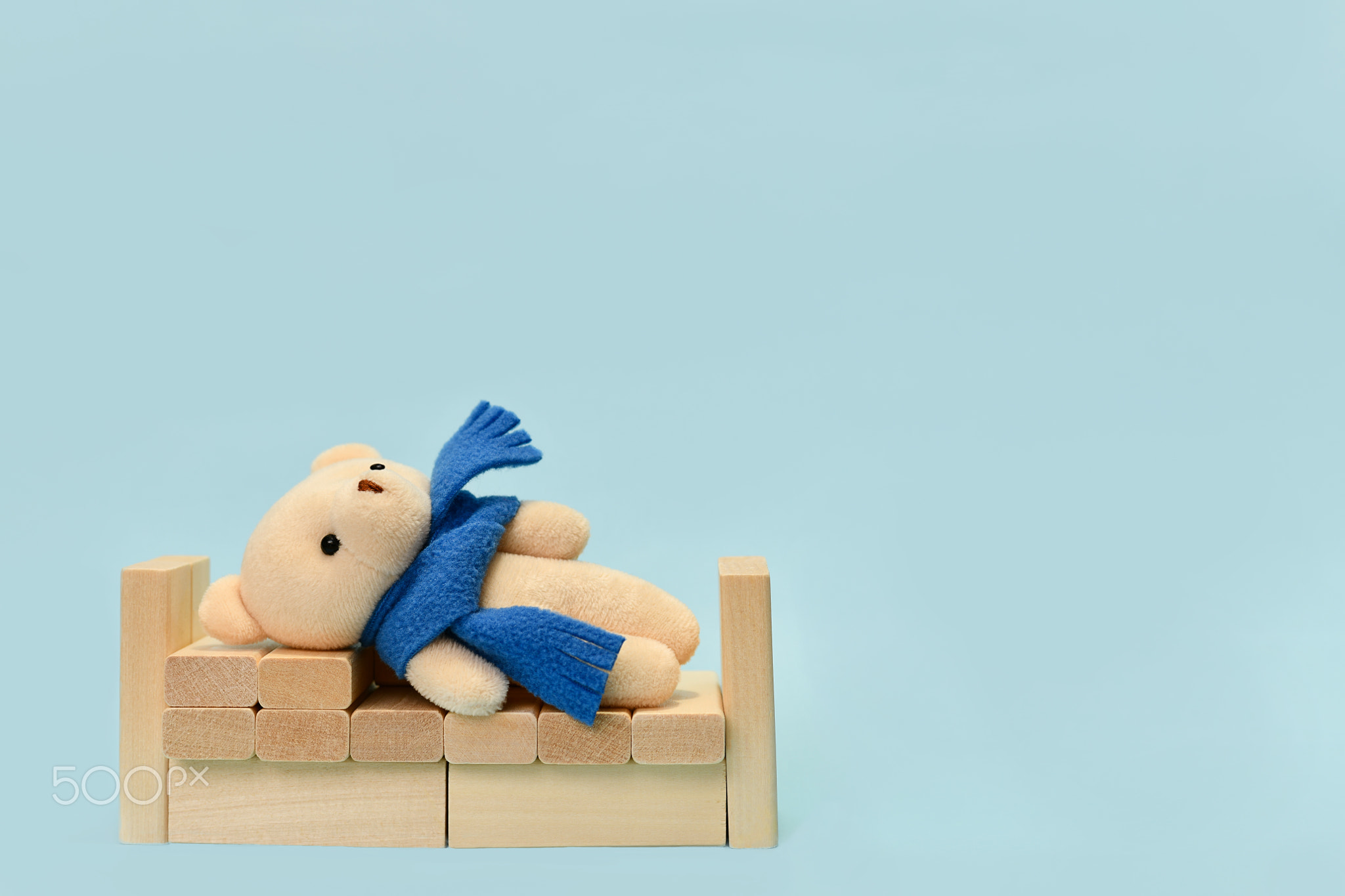 Sleeping in a crib toy bear in a blue scarf.