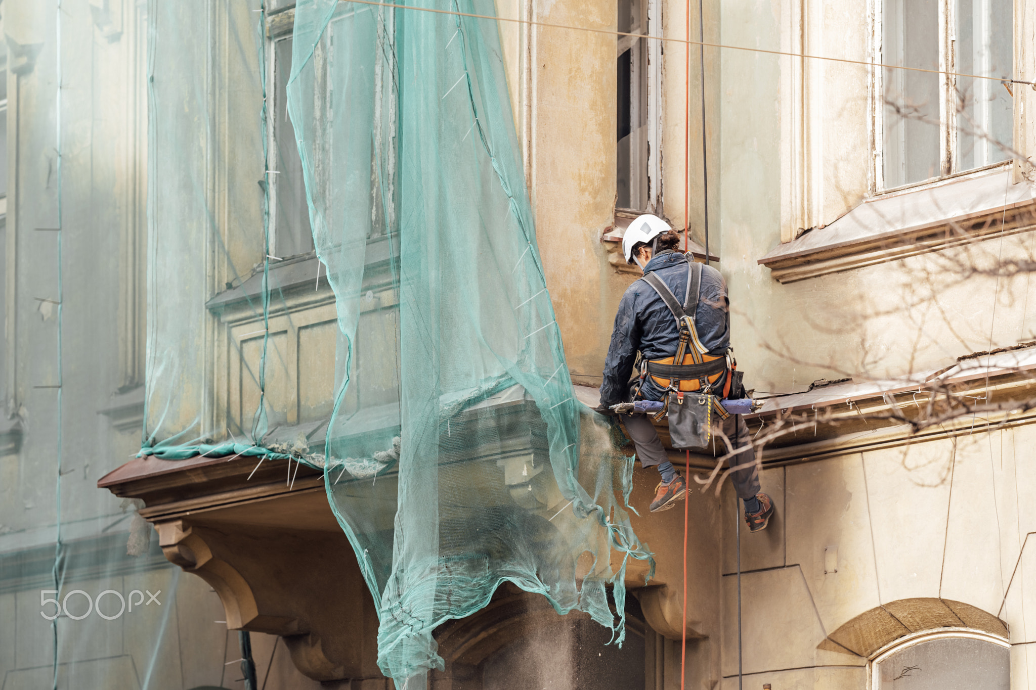 repair of the facade of the house by a man on suspension ropes