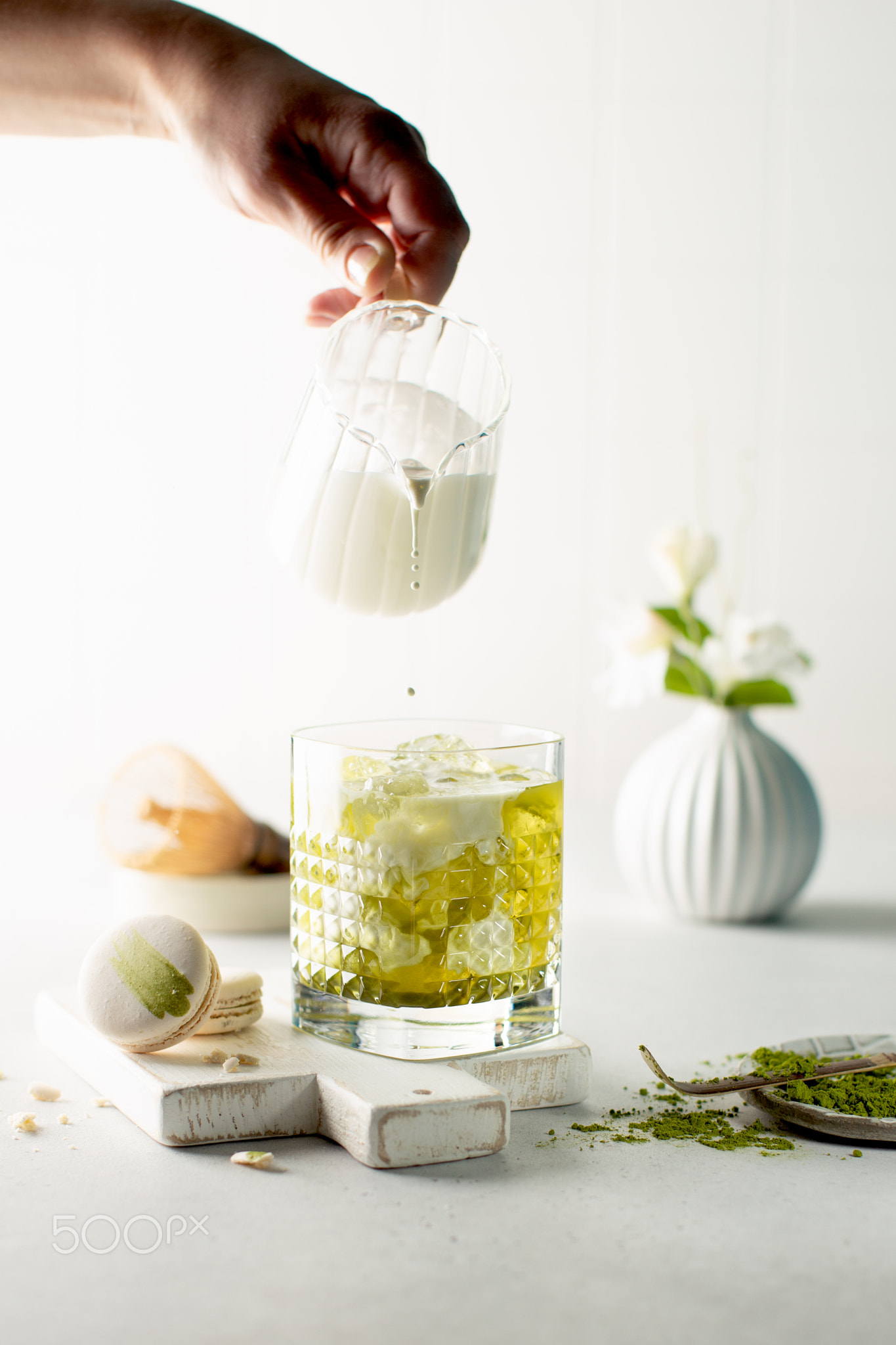 Iced green Matcha tea with pouring milk in glass,sweet macaroon and