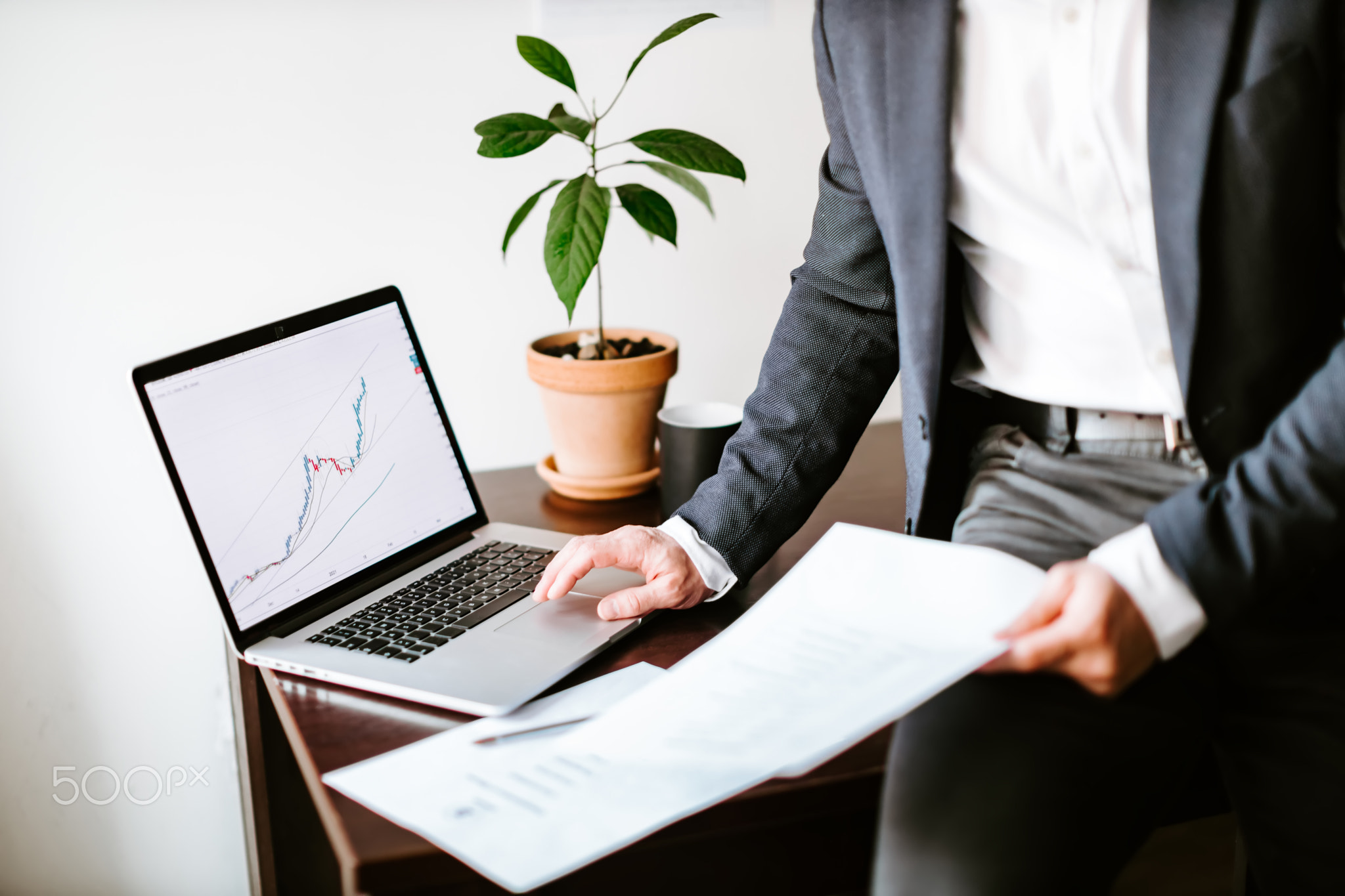 financial manager analyzing price data trend graph on laptop in office