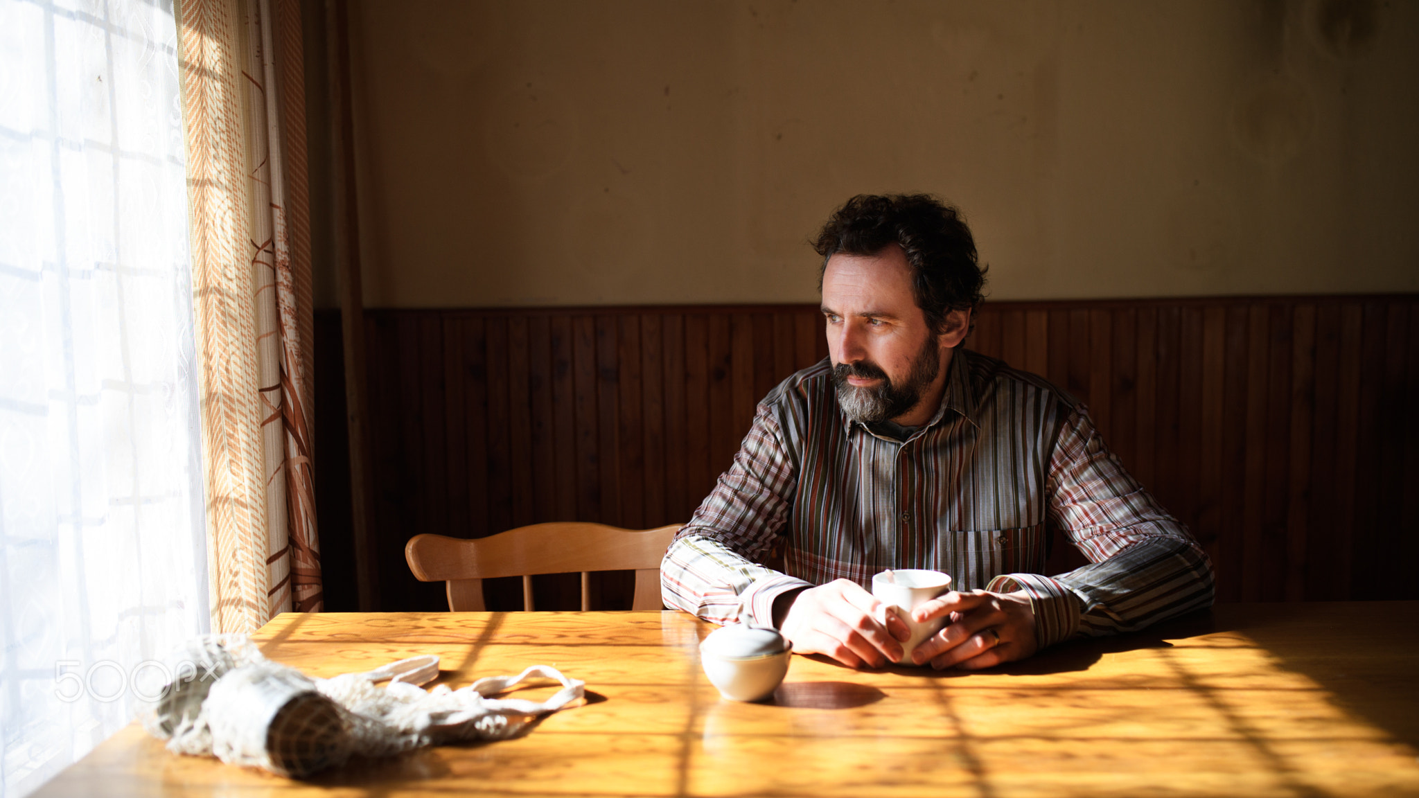 Portrait of unhappy poor mature man reading newspapers indoors at home